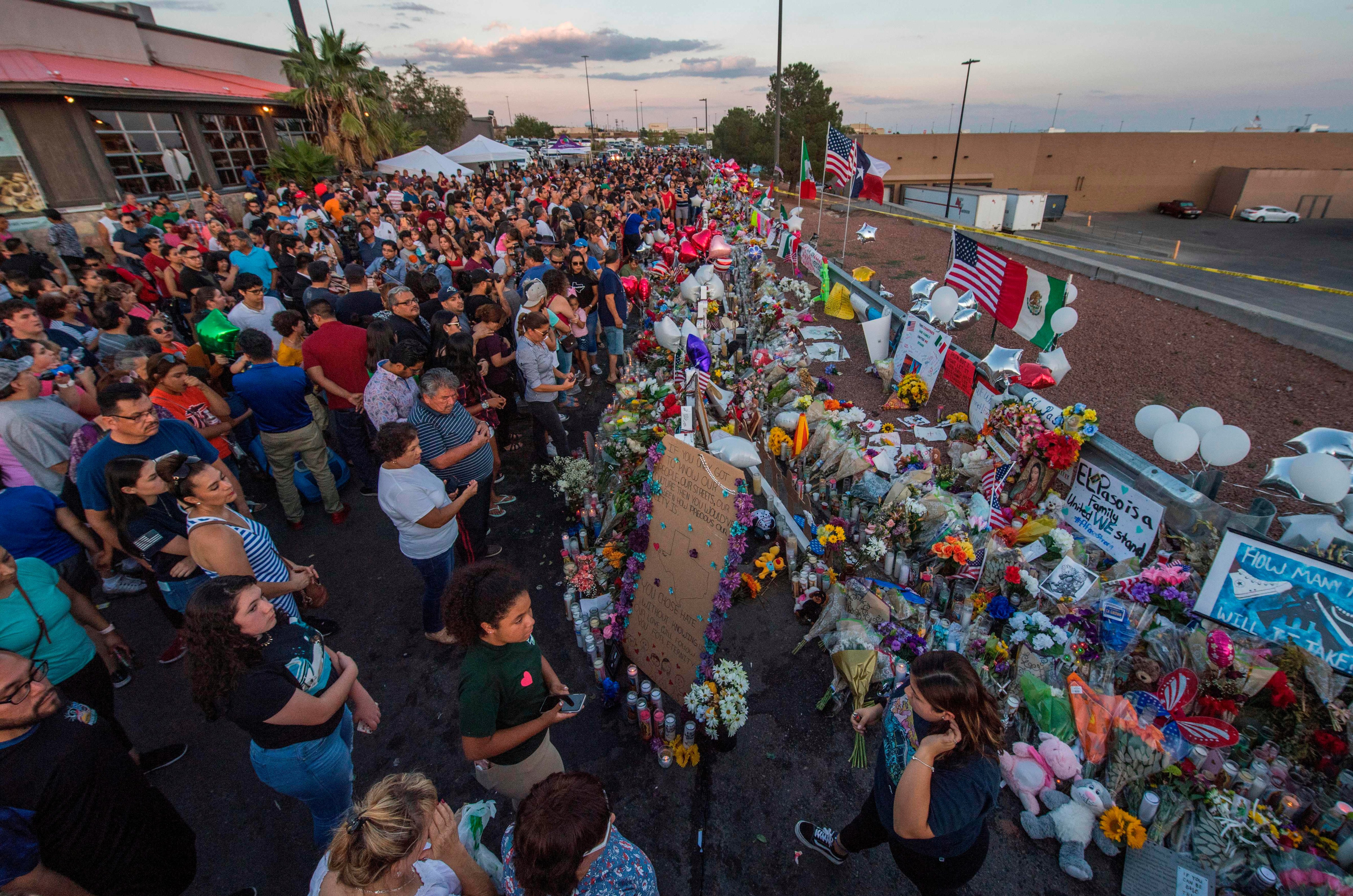 People pray and pay their respects at the makeshift memorial for victims of the shooting that left a total of 22 people dead at the Cielo Vista Mall WalMart (background) in El Paso, Texas, on August 6, 2019. - US President Donald Trump on Monday urged Republicans and Democrats to agree on tighter gun control and suggested legislation could be linked to immigration reform after two shootings left 30 people dead and sparked accusations that his rhetoric was part of the problem. (MARK RALSTON&mdash;AFP/Getty Images)