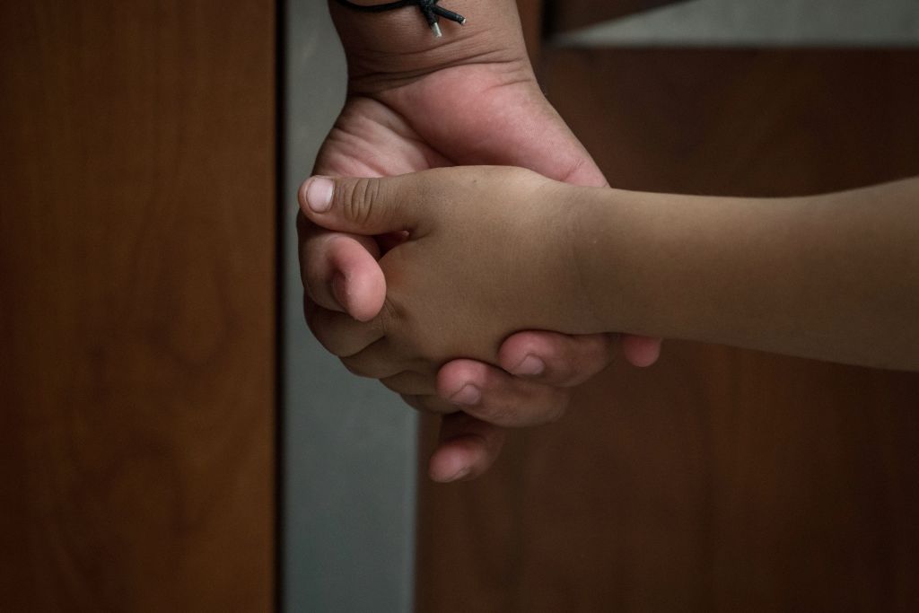 A Honduran asylum seeker, recently released from federal detention with fellow migrants, holds the hand of her six-year-old daughter at a bus depot on June 11, 2019, in McAllen, Texas. (LOREN ELLIOTT&mdash;AFP/Getty Images)