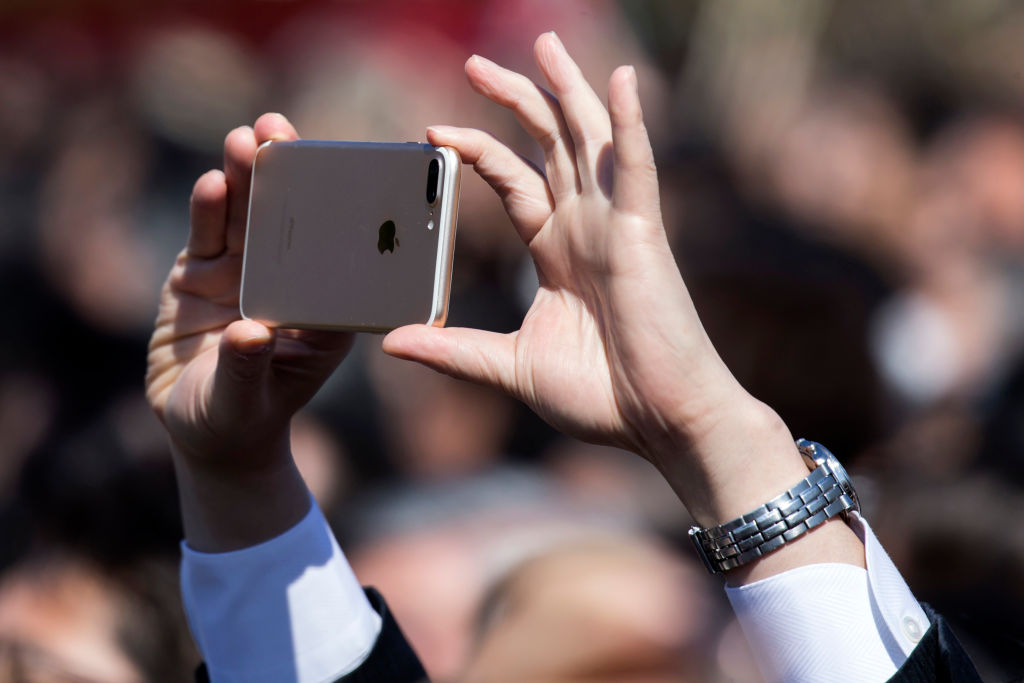 A guest attendee uses an Apple Inc.  iPhone to take a photograph of Japan's Prime Minister Shinzo Abe (not pictured) during the cherry blossom viewing party at the Shinjuku Gyoen National Garden on April 13, 2019 in Tokyo, Japan. (Tomohiro Ohsumi&mdash;Getty Images)