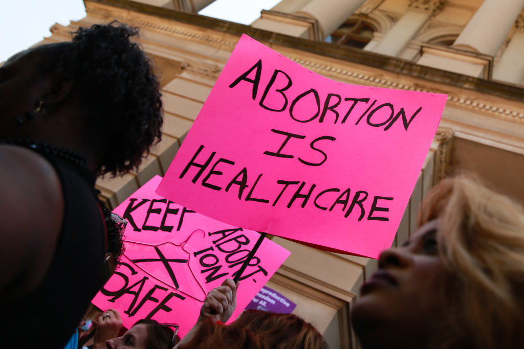 People hold signs during a protest against recently passed abortion ban bills at the Georgia State Capitol building, on May 21, 2019 in Atlanta, Georgia. The Georgia 