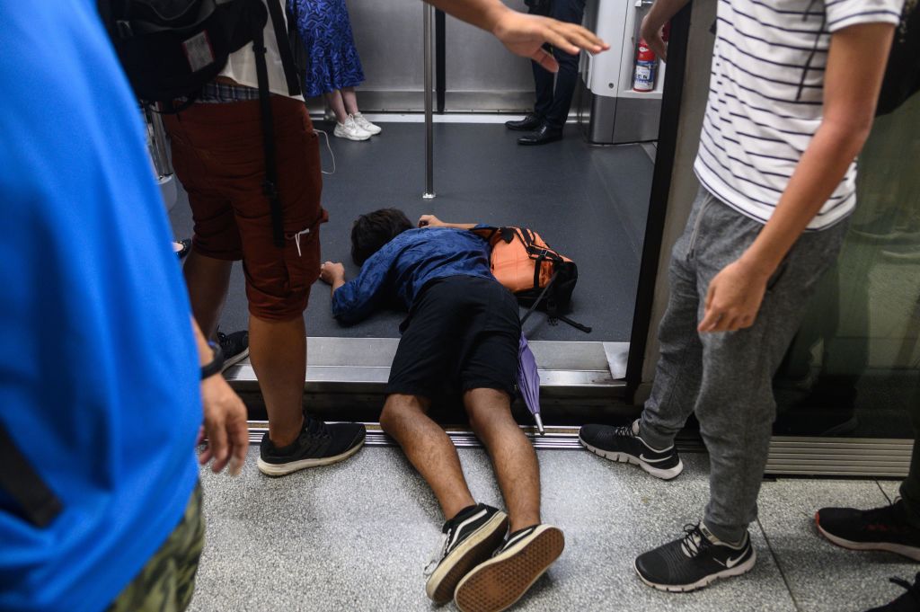 A man (C) falls down during a protest to prevent commuters from reaching work in business districts at Lai King MTR station in Hong Kong on August 5, 2019. (Philip Fong—AFP/Getty Images)
