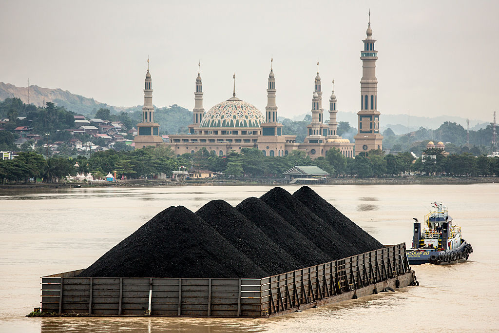 A tug pulls a coal barge past the Islamic centre in Samarinda, Kalimantan, Indonesia on Aug. 26, 2016. (Ed Wray&mdash;Getty Images)