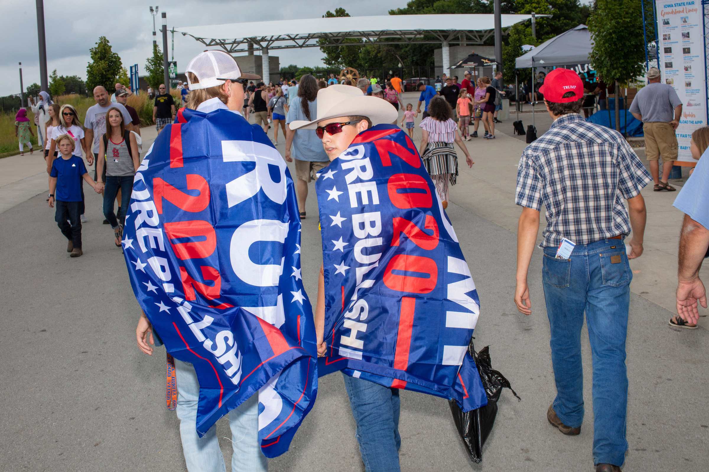 People wearing Trump flags walked ahead of the media scrum as Democratic presidential candidate Bernie Sanders walked along the midway at the Iowa State Fair in Des, Moines, Iowa, on Sun., Aug. 11, 2019.