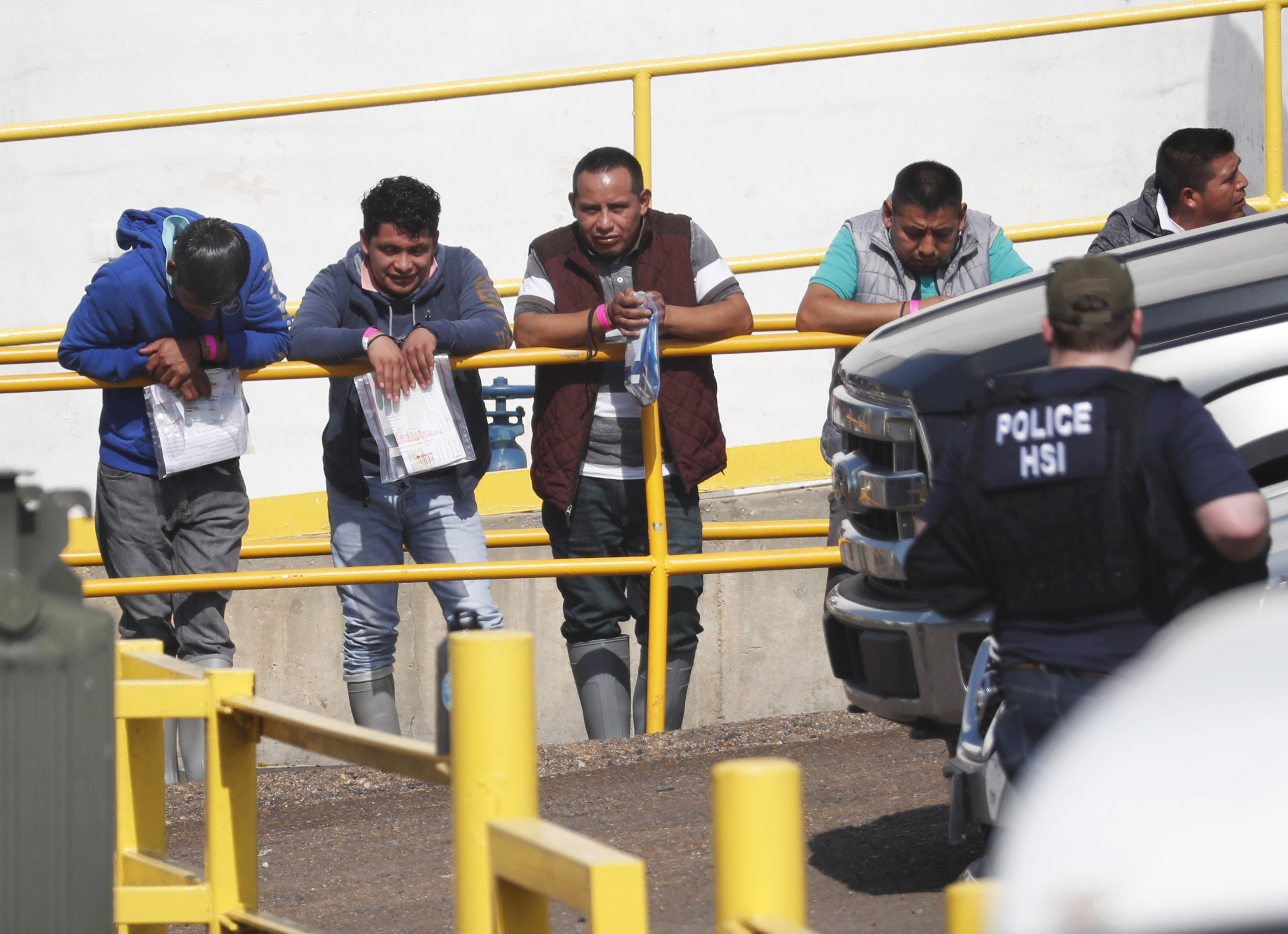 Handcuffed workers await transportation to a processing center following a raid by U.S. immigration officials at Koch Foods Inc., plant in Morton, Miss. (Rogelio V. Solis—AP)