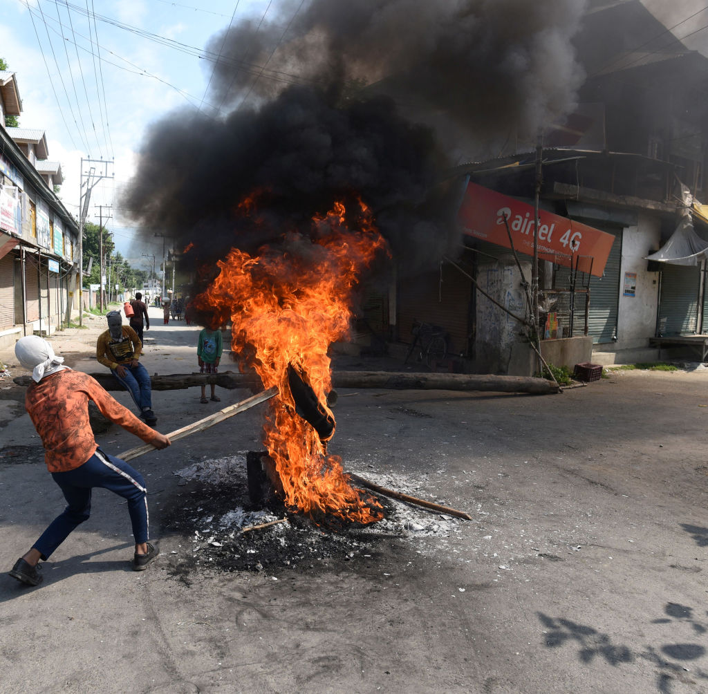 A protester holds a burning tire near a barricade set by the local protesters to block the road during a protest against the abolishing of Article 370, on August 20, 2019 on the outskirts of Srinagar, India. (Waseem Andrabi/Hindustan Times—Getty Images)
