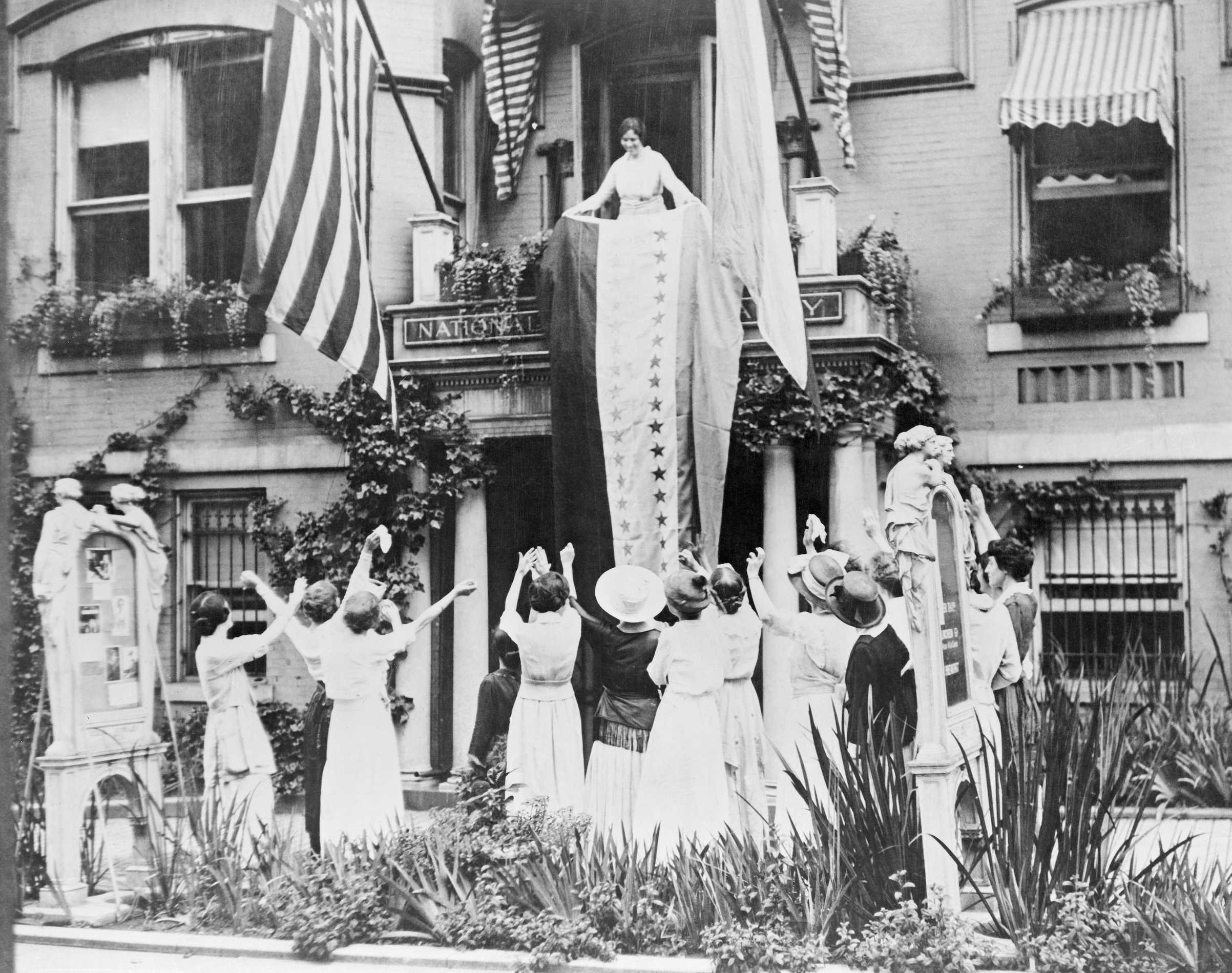 Alice Paul unfurls a banner from the balcony of the National Women's Party headquarters, celebrating the ratification of the 19 Amendment by Tennessee. (Bettmann/Getty Images)