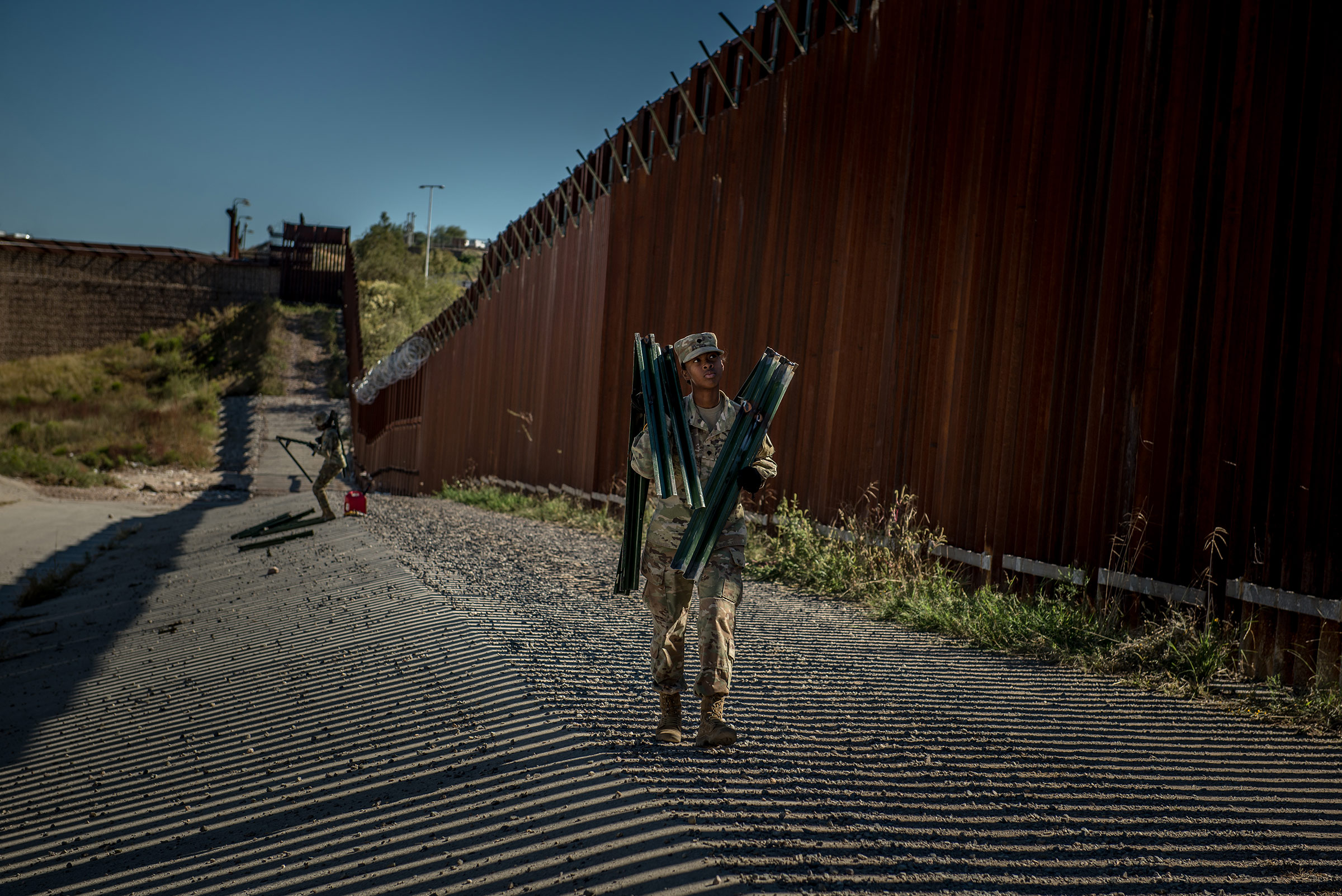 Soldiers install brackets and wire along the border wall in November. (Meridith Kohut for TIME)