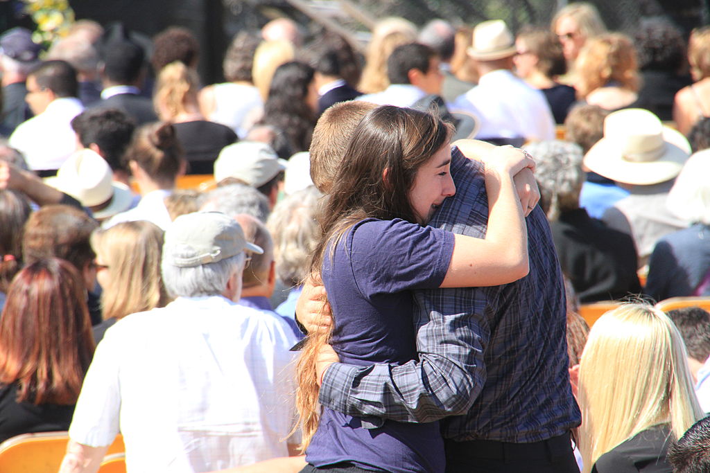 A couple comfort one another before the start of a memorial service at UC Santa Barbara's Harder Stadium to honor six UCSB students slain in a rampage in Isla Vista, California. (Patricia Marroquin—Moment Editorial/Getty Images)