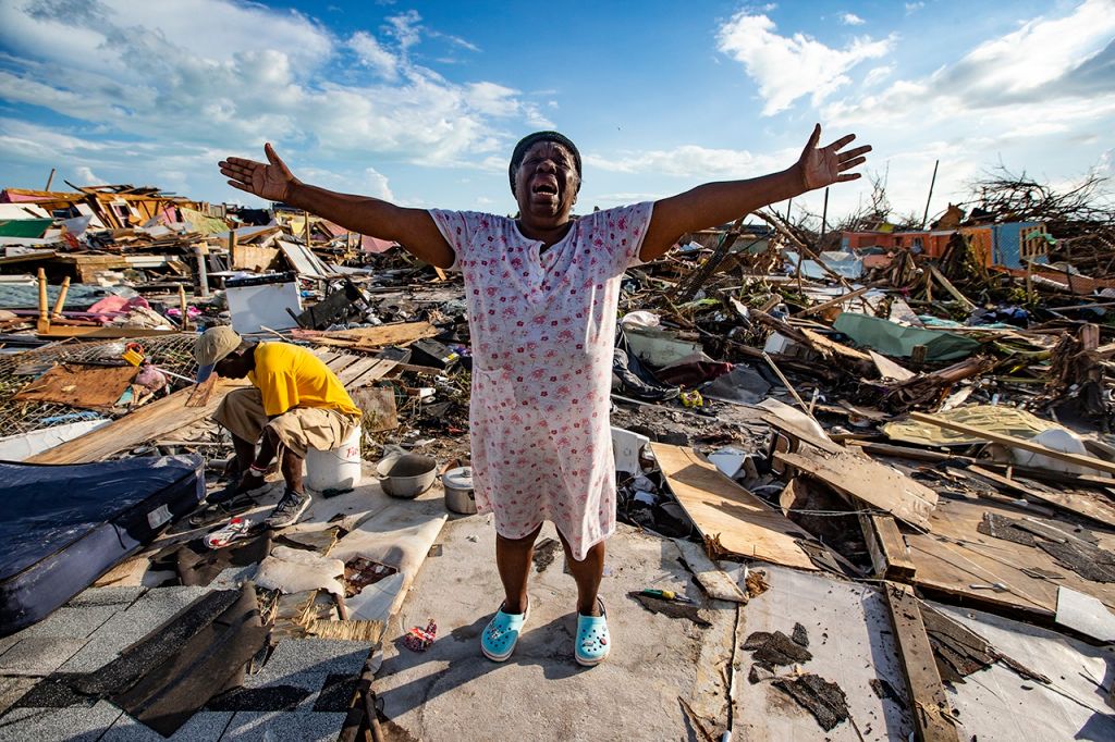 Aliana Alexis of Haiti stands on the concrete slab of what is left of her home after destruction from Hurricane Dorian in an area called 