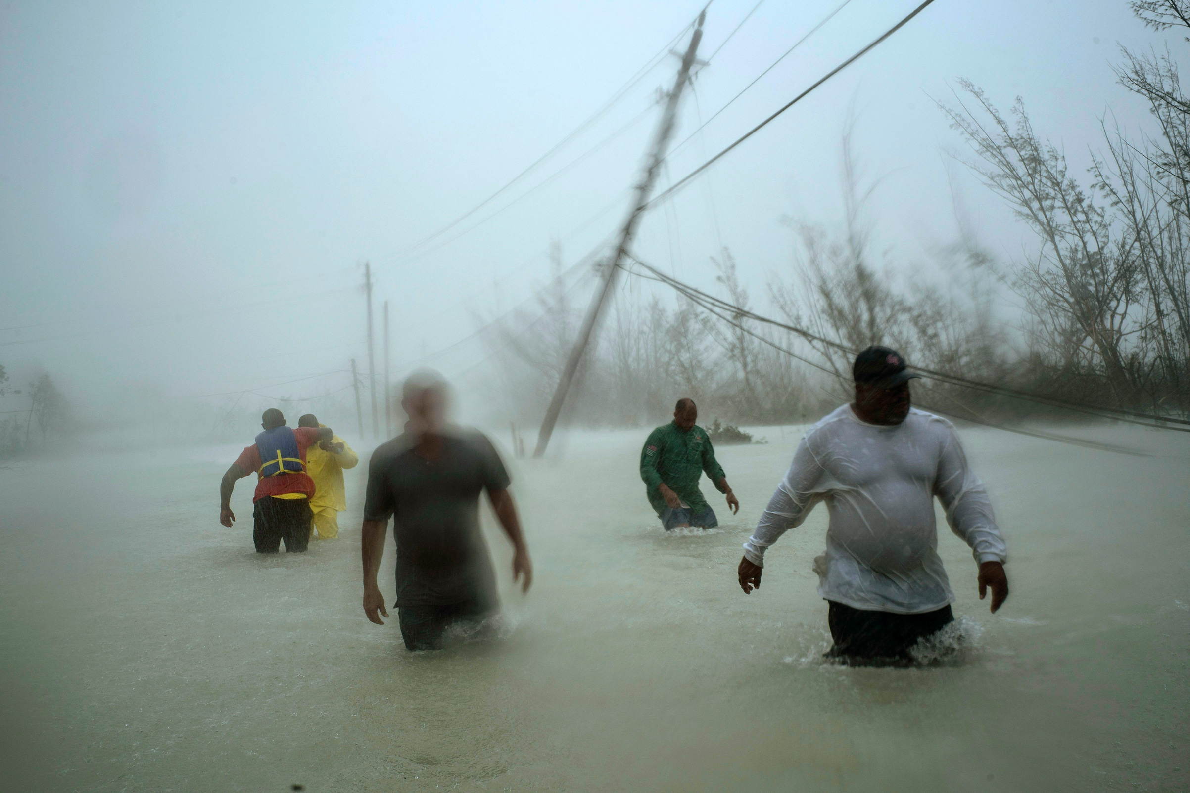 Volunteers wade through a flooded road against wind and rain caused by Hurricane Dorian to rescue families near the Causarina bridge in Freeport, Grand Bahama, Bahamas, Sept. 3, 2019. The storm's winds and muddy floodwaters devastated thousands of homes, crippled hospitals and trapped people in attics. (Ramon Espinosa—AP)