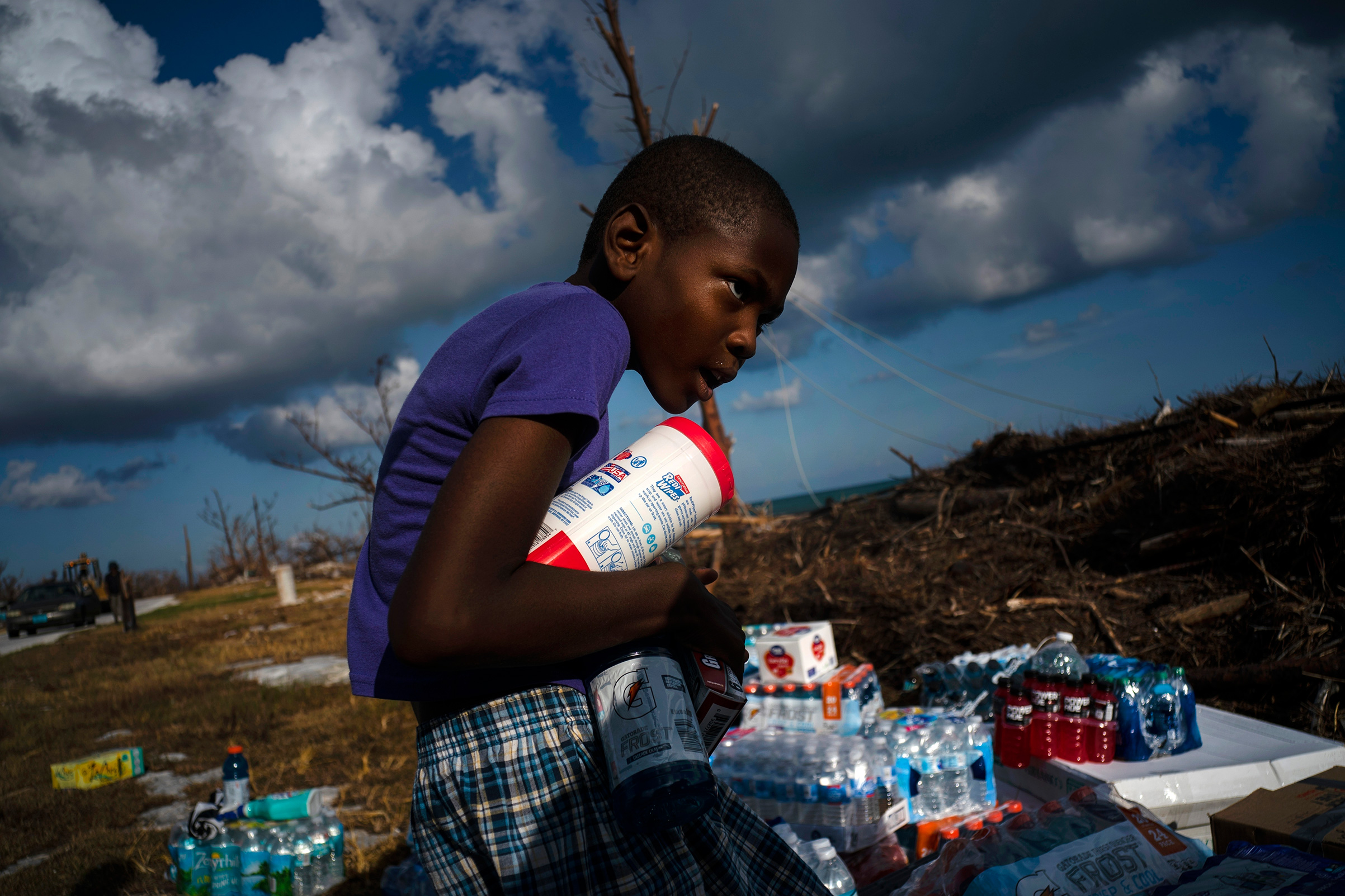 Ayfon Minus, 8, collects donated food that was brought by helicopter from Freeport to the Hurricane Dorian destroyed village of High Rock, Grand Bahama, Bahamas, Sept. 10, 2019. (Ramon Espinosa—AP)