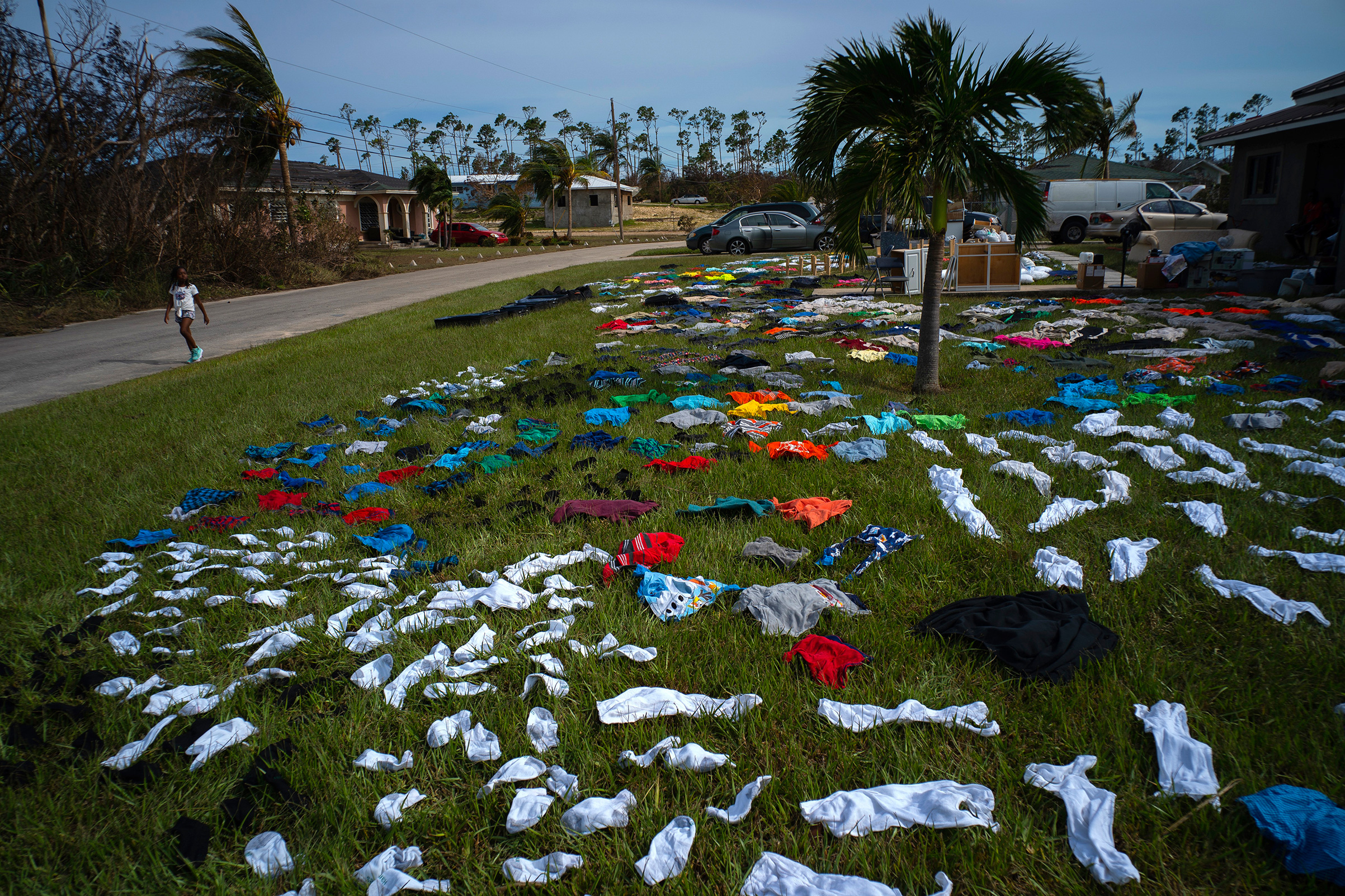 A child walks past clothes laid out to dry on a field in the aftermath of Hurricane Dorian in the Arden Forest neighborhood of Freeport, Bahamas, Sept. 4, 2019. (Ramon Espinosa—AP)