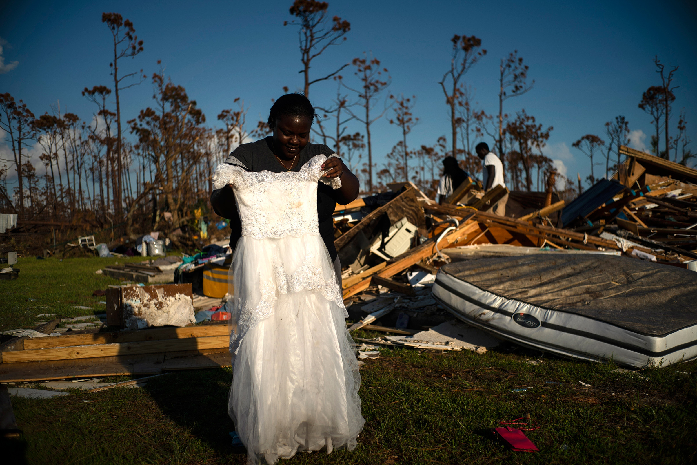 Synobia Reckley holds up the dress her niece wore as a flower girl at her wedding, as she goes through valuables in the rubble of her home destroyed one week ago by Hurricane Dorian in Rocky Creek East End, Grand Bahama, Bahamas, Sept. 8, 2019. (Ramon Espinosa—AP)