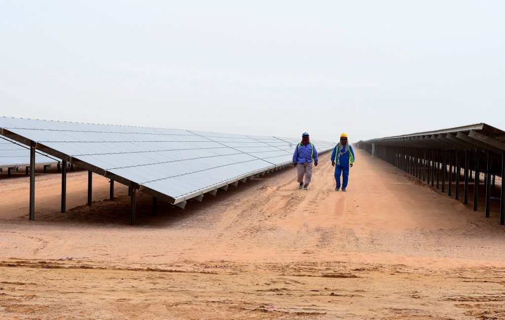 Employees walk past solar panels at the Mohammed bin Rashid Al-Maktoum Solar Park on March 20, 2017, in Dubai. (STRINGER—AFP/Getty Images)