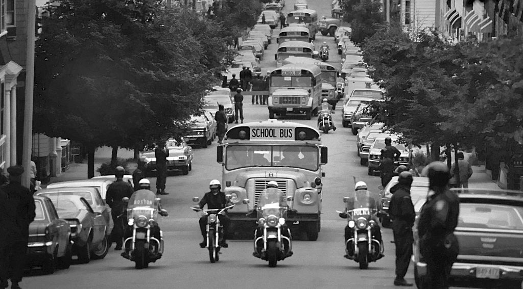 Accompanied by motorcycle-mounted police, school buses carrying African American students arrive at formerly all-white South Boston High School on September 12, 1974. In 1971, the U.S. Supreme Court ruled in favor of busing as a mechanism to end racial segregation because black children were still attending segregated schools. White children had been riding school buses for decades, but the idea of using the same mechanism to desegregate public schools triggered violent protests, writes Gloria J. Browne-Marshall. (Spencer Grant&mdash;Getty Images)