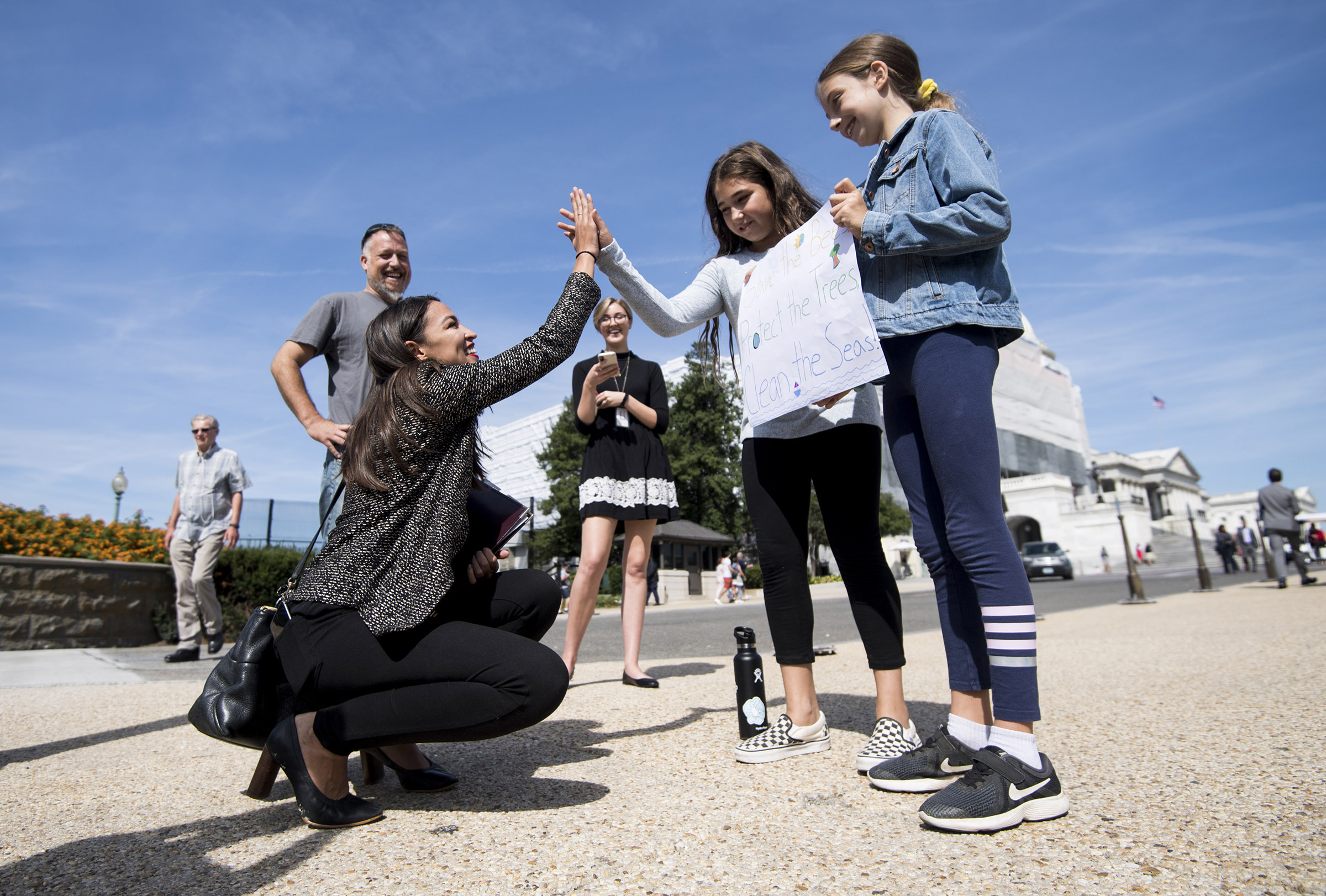 Rep. Alexandria Ocasio-Cortez, D-N.Y., high-fives climate striking students Evelyn Seek, center, and Pema Duncan, right, as they hold their climate strike sign in front of the Capitol on Friday, Sept. 20, 2019. (Bill Clark—CQ-Roll Call via Getty Images)