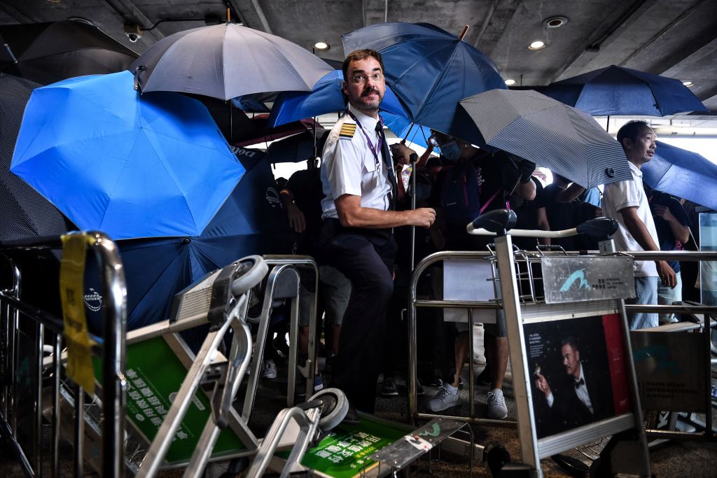 An airline crew member makes his way through a barrier set up by protesters at Hong Kong International Airport on September 1, 2019. - Hundreds of Hong Kong pro-democracy activists attempted to block transport routes to the city's airport on September 1, as the financial hub began cleaning up after another night of serious violence marked by fires, tears gas and police beatings. (Photo by Lillian SUWANRUMPHA / AFP)        (Photo credit should read LILLIAN SUWANRUMPHA/AFP/Getty Images) (Lillian Suwanrumpha&mdash;AFP/Getty Images)