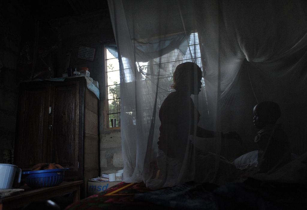A mother and her child sit on a bed covered with a mosquito net in Tanzania on October 30, 2009. (TONY KARUMBA&mdash;AFP/Getty Images)