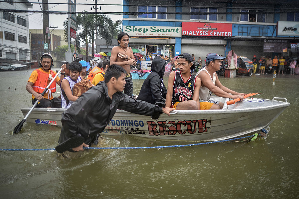 Жертв наводнения эвакуируют на спасательной лодке после того, как их дома были затоплены сильным наводнением в городе Кесон, пригород Манилы, Филиппины, 19 сентября 2014 г. (NurPhoto—Corbis через Getty Images)