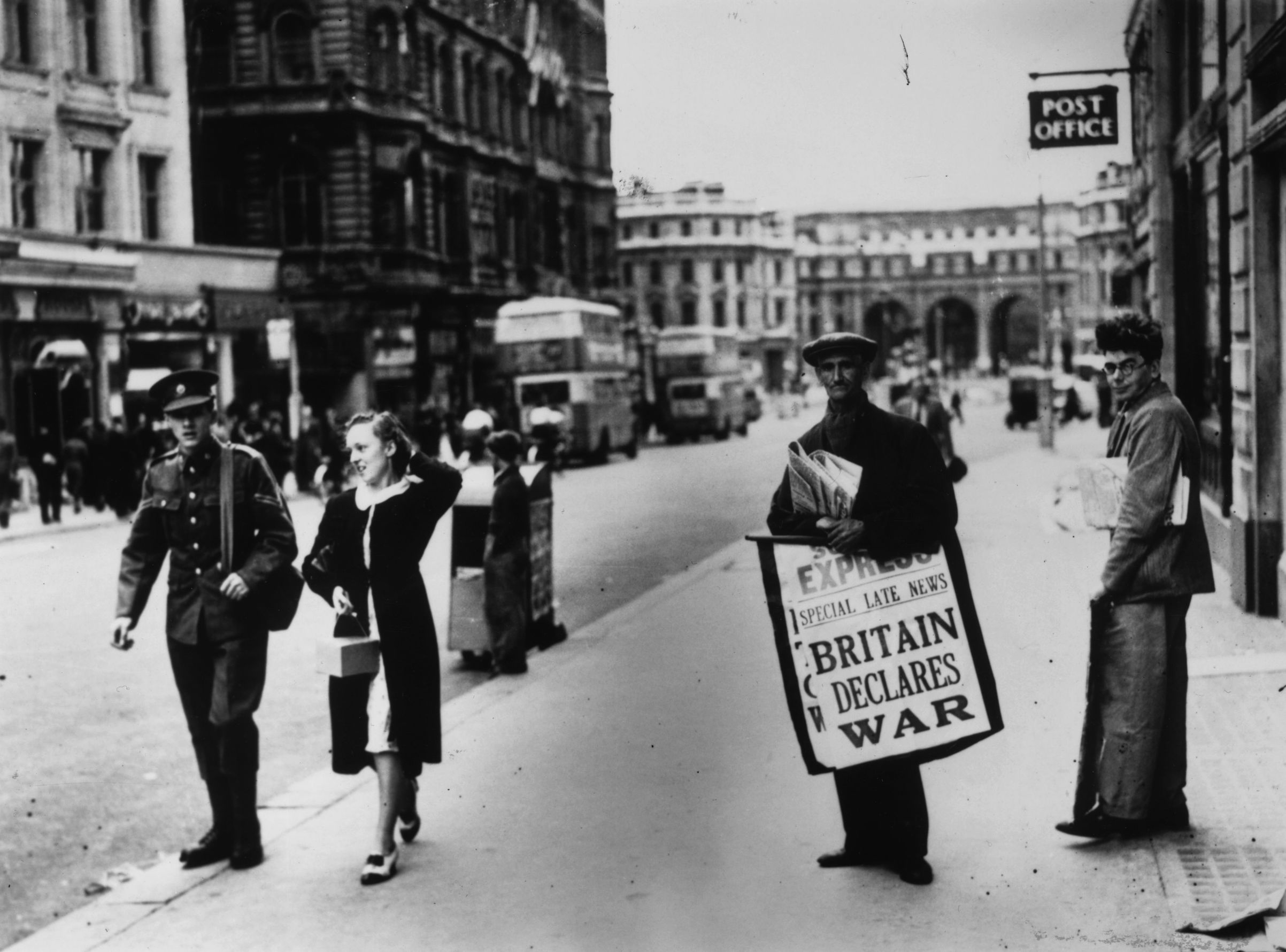 On Sept. 3, 1939, a newspaper seller carries a board  pronouncing the declaration of war between Britain and Germany, on the Strand, heading towards Admiralty Arch in London. (Central Press/Getty Images)