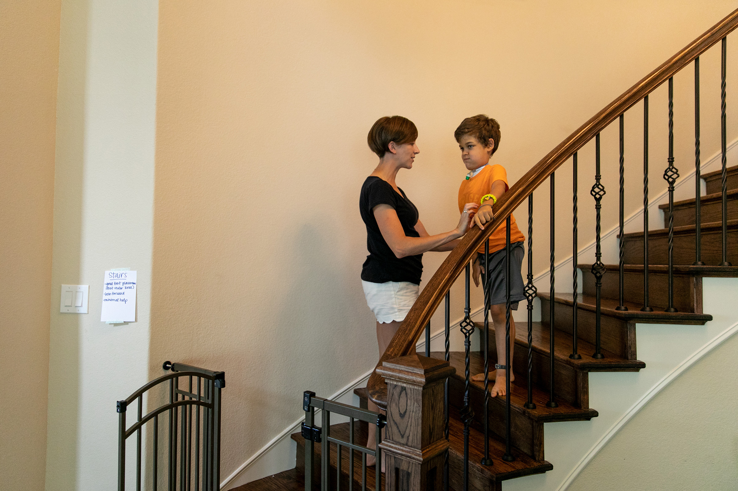 Rachel Scott helps her son Braden walk down the stairs in their home.