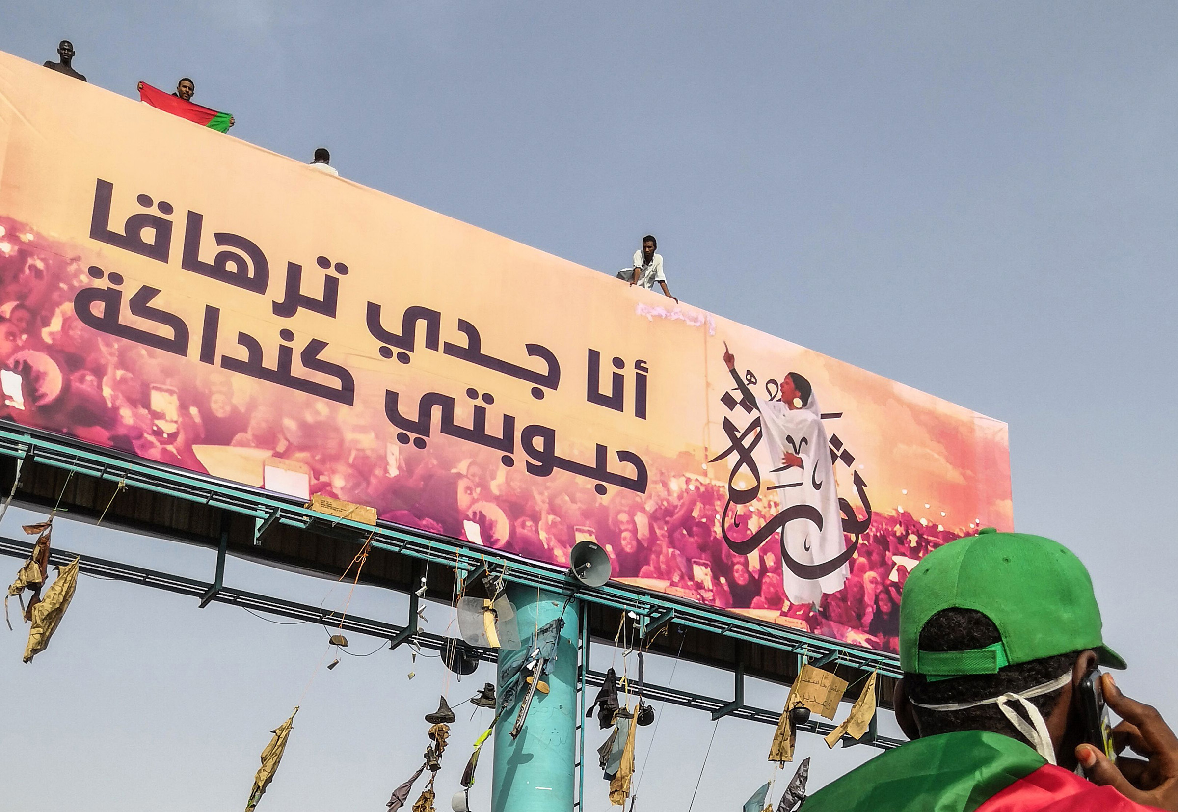 A Sudanese anti-regime protester speaks on his mobile telephone in Khartoum as he walks past a huge billboard bearing an image of Alaa Salah on on April 11, 2019. (AFP/Getty Images)