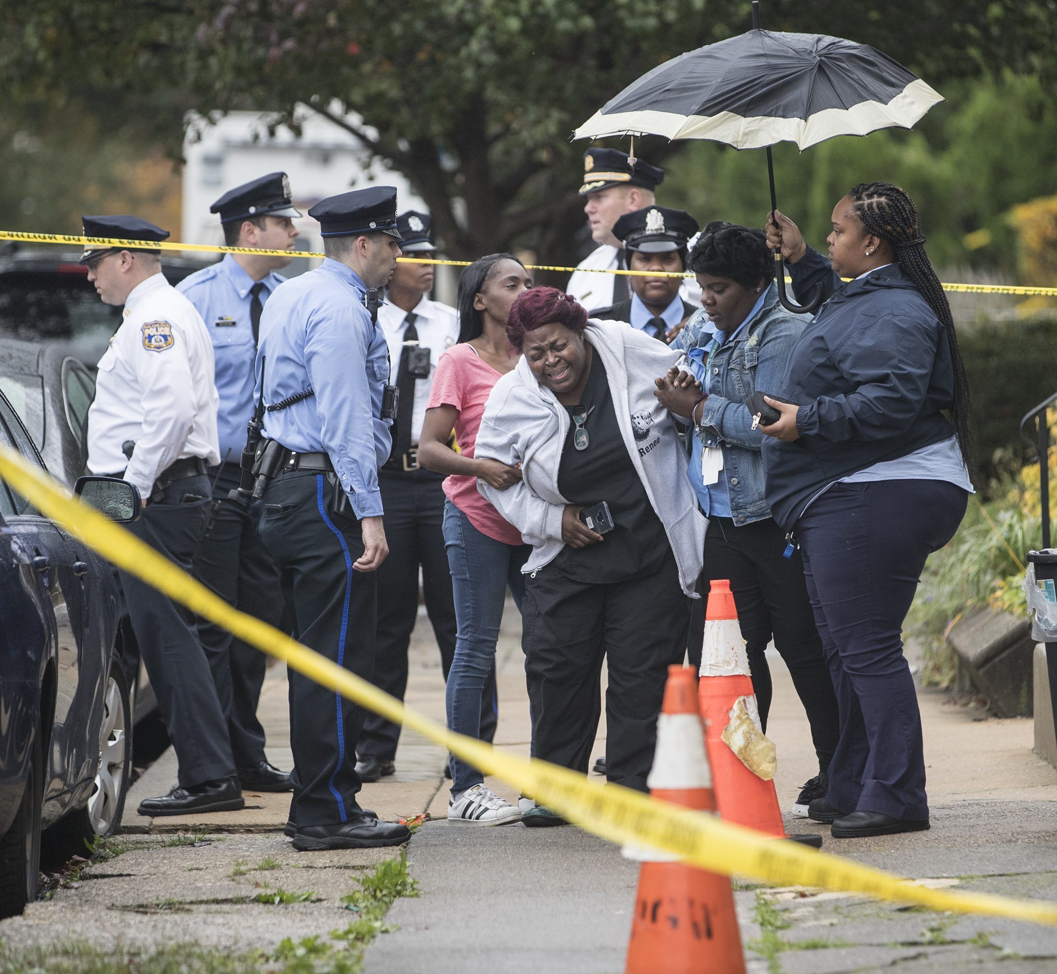 A grieving woman is assisted outside a home where four people were found shot dead on Oct. 30, 2019, in west Philadelphia. (Charles Fox&mdash;AP)