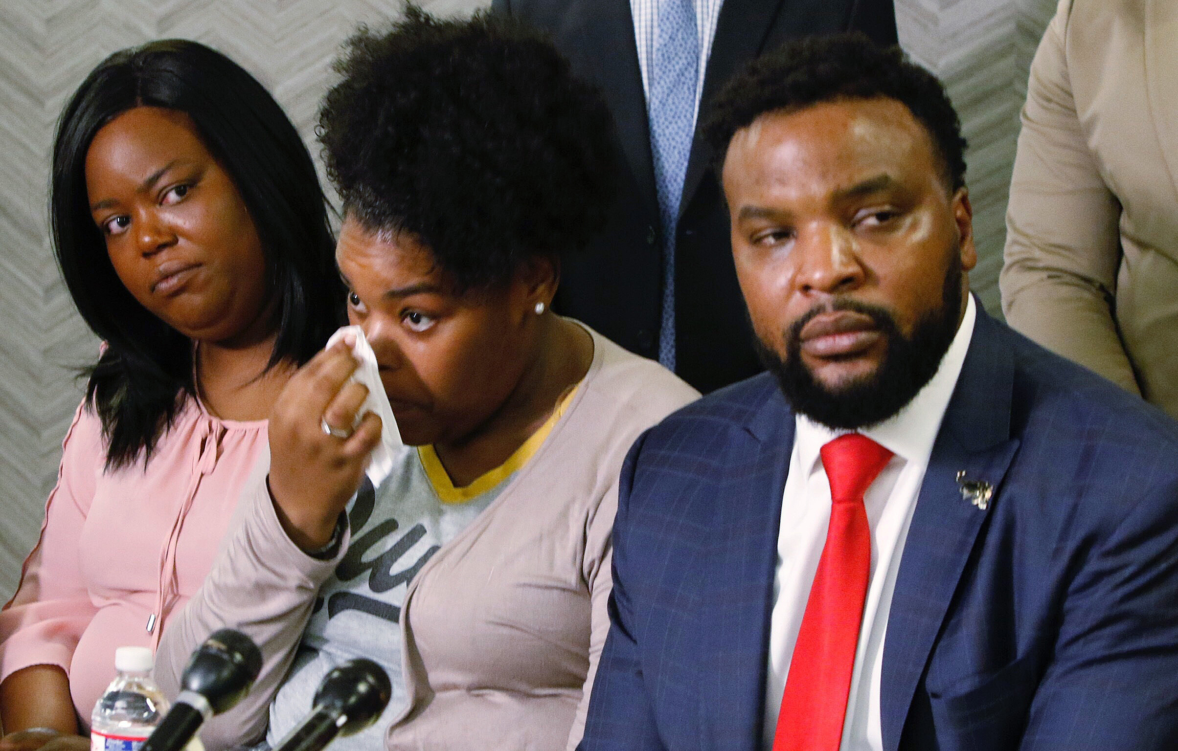 Amber Carr, center, wipes a tear as her sister, Ashley Carr, left, and attorney Lee Merritt, right, listen to Amber and Ashley's brother Adarius Carr talk about their sister Atatiana Jefferson during a news conference, Monday, Oct. 14, 2019, in downtown Dallas. (Irwin Thompson—AP)