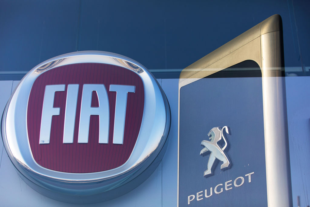 The logos of Fiat Chrysler Automobiles NV and Peugeot, a unit of PSA Group, sit on display in automobile showrooms in Dubai, United Arab Emirates, on Oct. 31, 2019. (Bloomberg&mdash;Bloomberg via Getty Images)