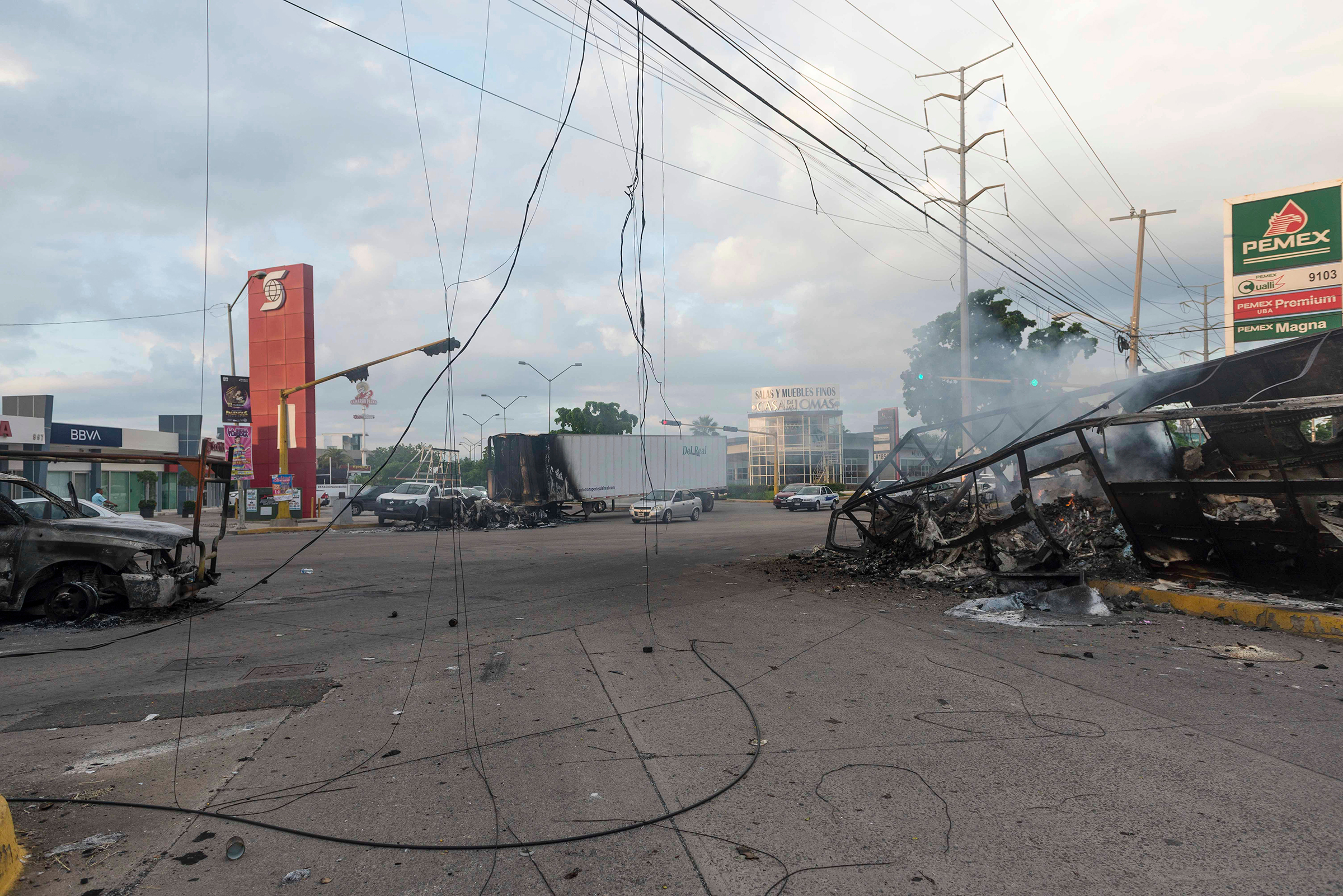 Burnt vehicles used by gunmen smolder on an intersection, one day after street battles with security forces, in Culiacan, Mexico, on Oct. 18, 2019.