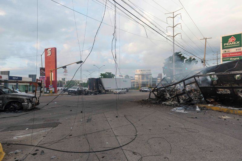 Burnt vehicles used by gunmen smolder on an intersection, one day after street battles with security forces, in Culiacan on Oct. 18.
