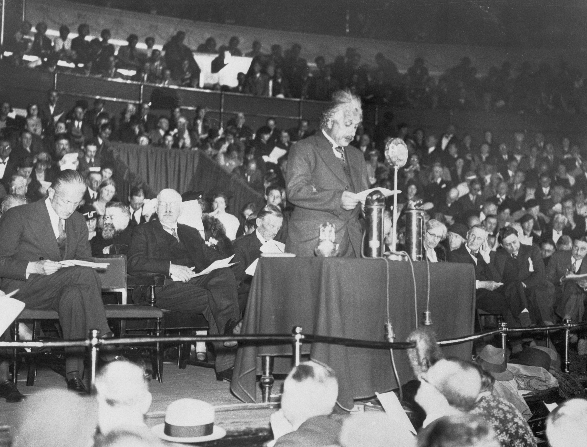 Professor Albert Einstein, who has taken up residence in England as a refugee from Nazi threats, was among the prominent speakers who addressed a great gathering at the Royal Albert Hall in London, recently, to aid the Jewish Refugee Fund. Commander Locker Lampson, M.P., Lord Rutherford and Sir Austen Chamberlain were among the principal speakers of the meeting. Photo shows Professor Einstein during the delivery of his speech. October 1933. (Bettmann/Getty Images)