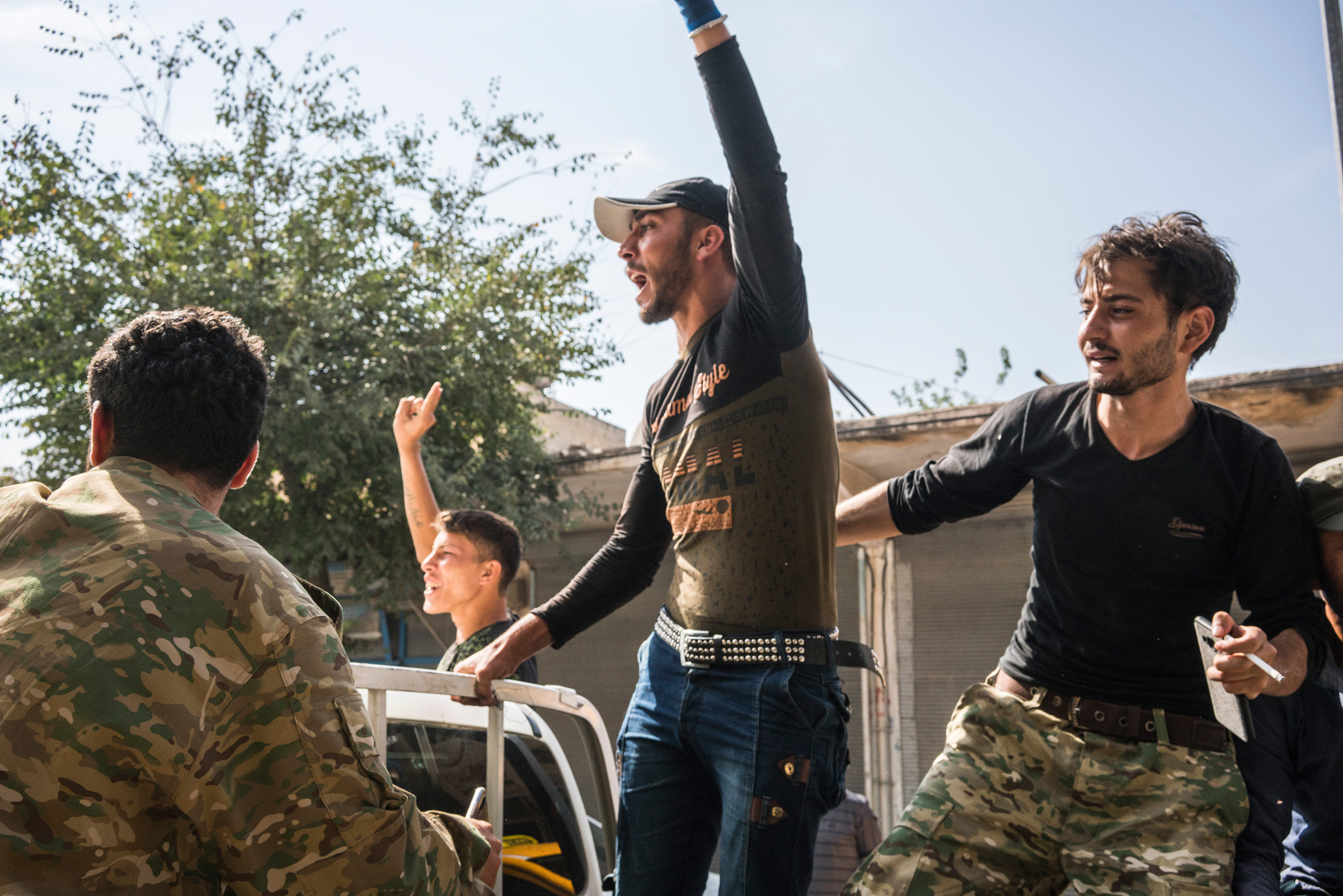 Turkish-backed Syrian rebels shout on the back of a pickup truck on a street in the Turkish border town of Akçakale on Oct. 14, 2019.