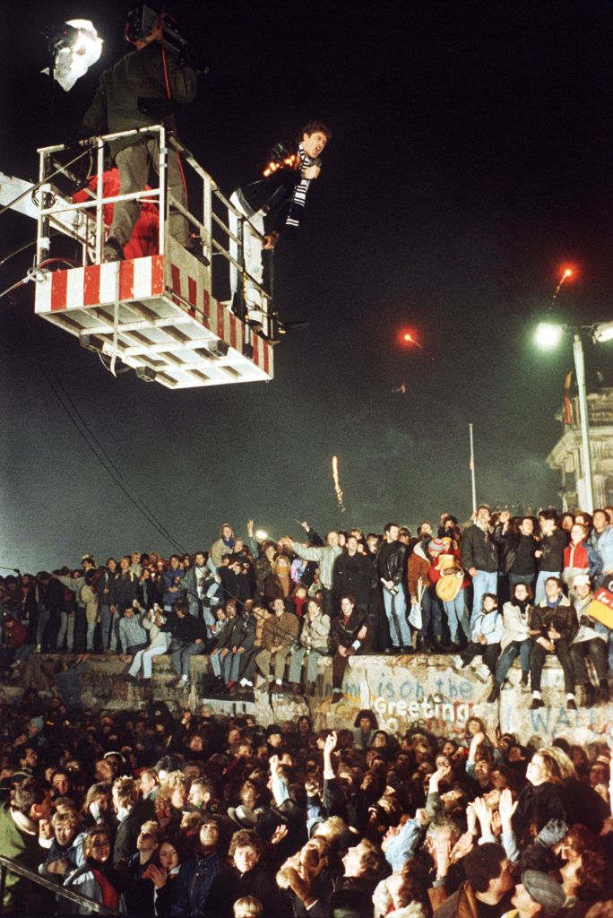 American singer and actor David Hasselhoff hovers in the cage of a hoisting crane above celebrating people on the Berlin Wall and sings "Looking for Freedom" during the first German-German New Year's Eve party on Dec. 31, 1989, at the Brandenburg Gate. (Wöstmann/picture alliance—Getty Images)
