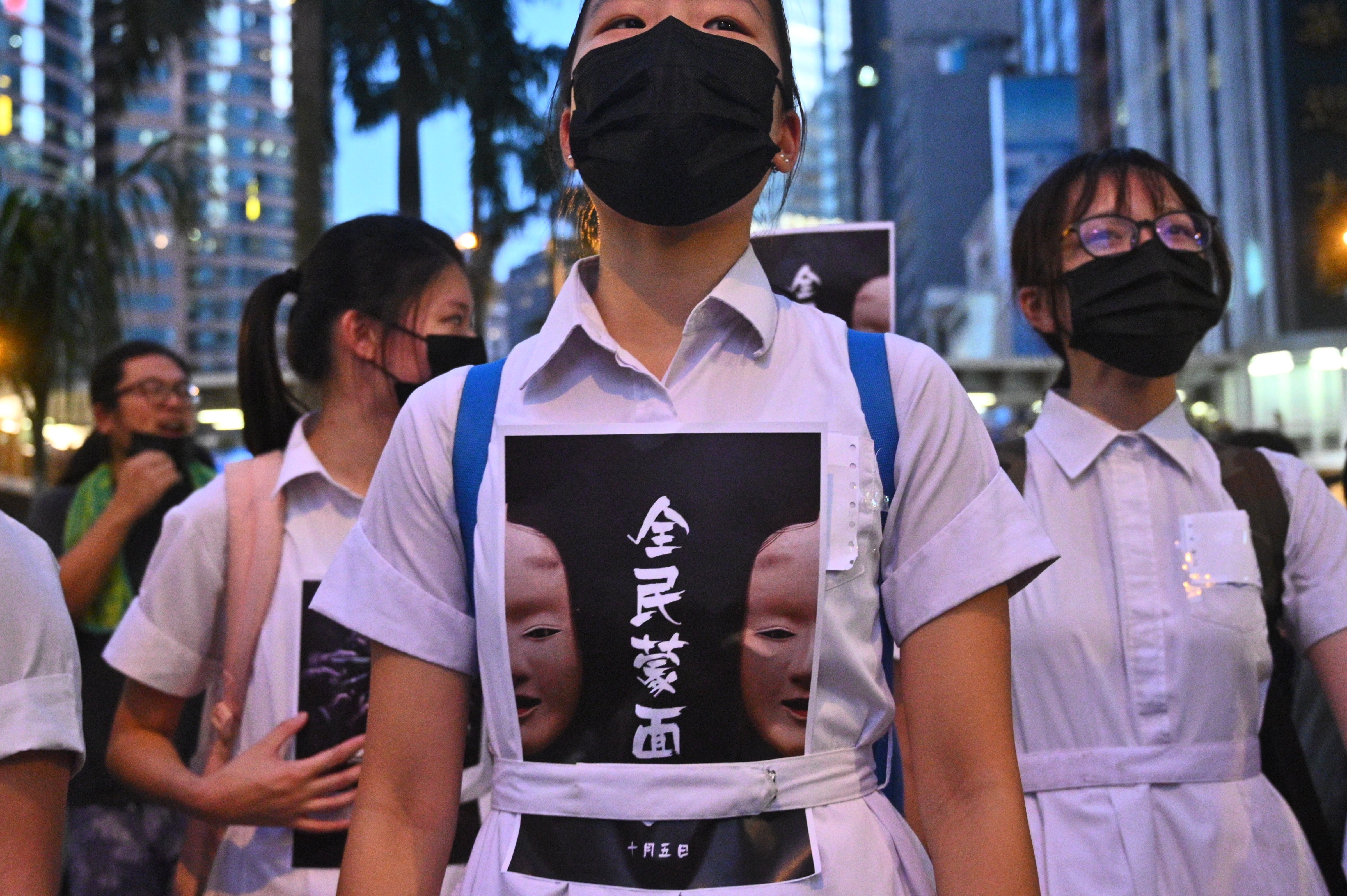 High school students chant slogans as they stick posters reading "all people masked" on their uniforms while protesters gather in the heart of Hong Kong's commercial district Central on October 4, 2019, after the government announced a ban on facemasks. (PHILIP FONG—AFP via Getty Images)