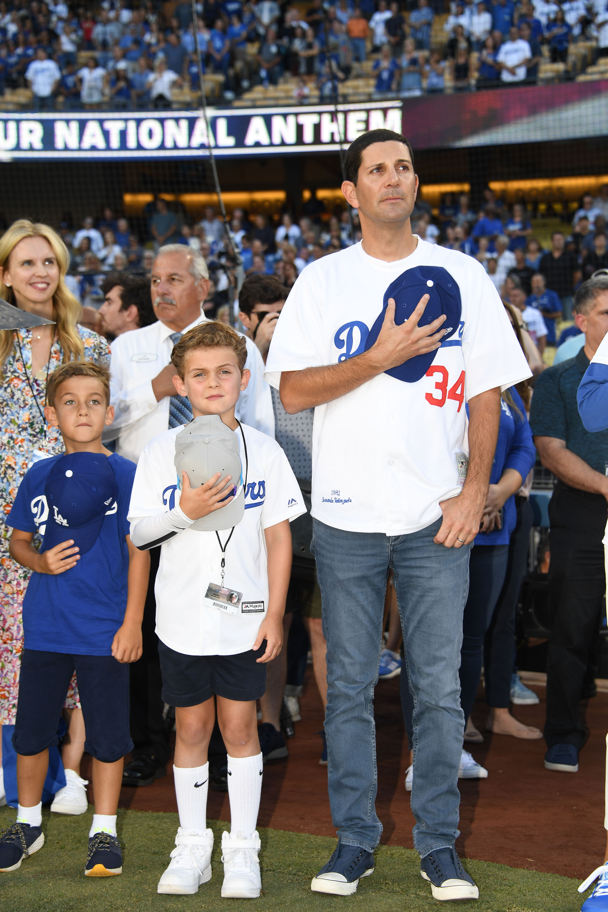 New Los Angeles Dodgers minority owner Alan Smolinisky, right, and his son Charlie Mario, in white jersey, stand for National Anthem at a Los Angeles Dodgers game at Dodger Stadium on September 21, 2019. (Jon SooHoo/LA Dodgers)