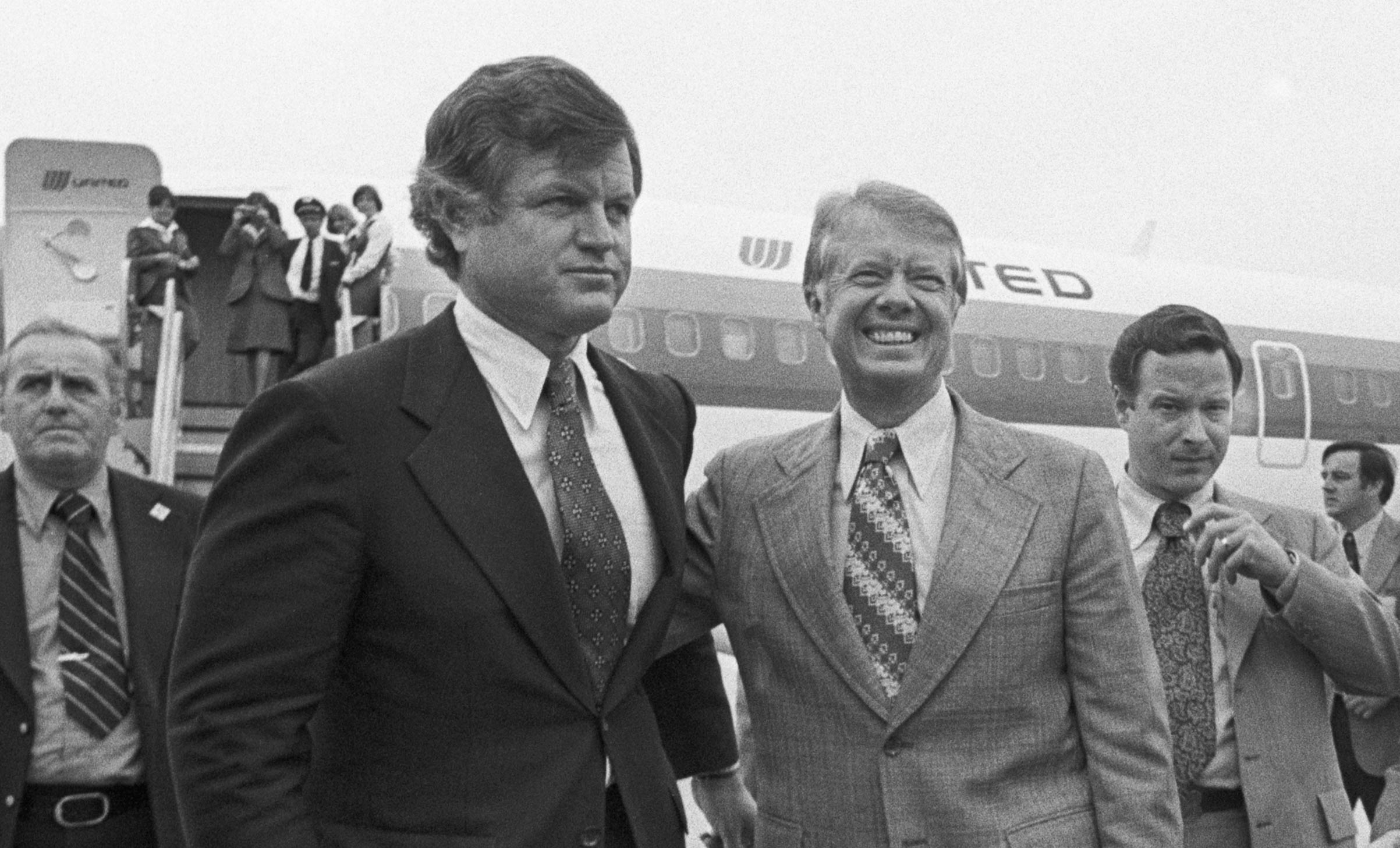 Pictured (center), Democratic presidential nominee Jimmy Carter, (R), puts his arm around Senator Edward M. Kennedy (L) as he arrived at Logan International Airport in Boston on Sep. 30, 1976, for a four-hour campaign blitz. (Bettmann/Getty)