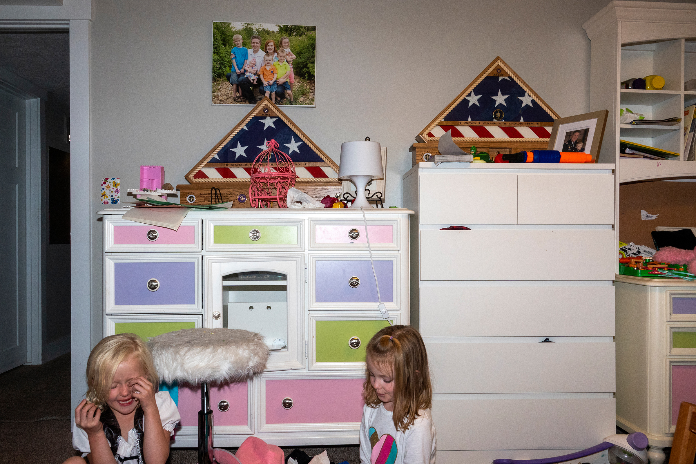 Ellie Taylor plays with cousin Vivian Pack in her bedroom. Resting on the dressers are two framed flags presented to each member of the family by the U.S. military.