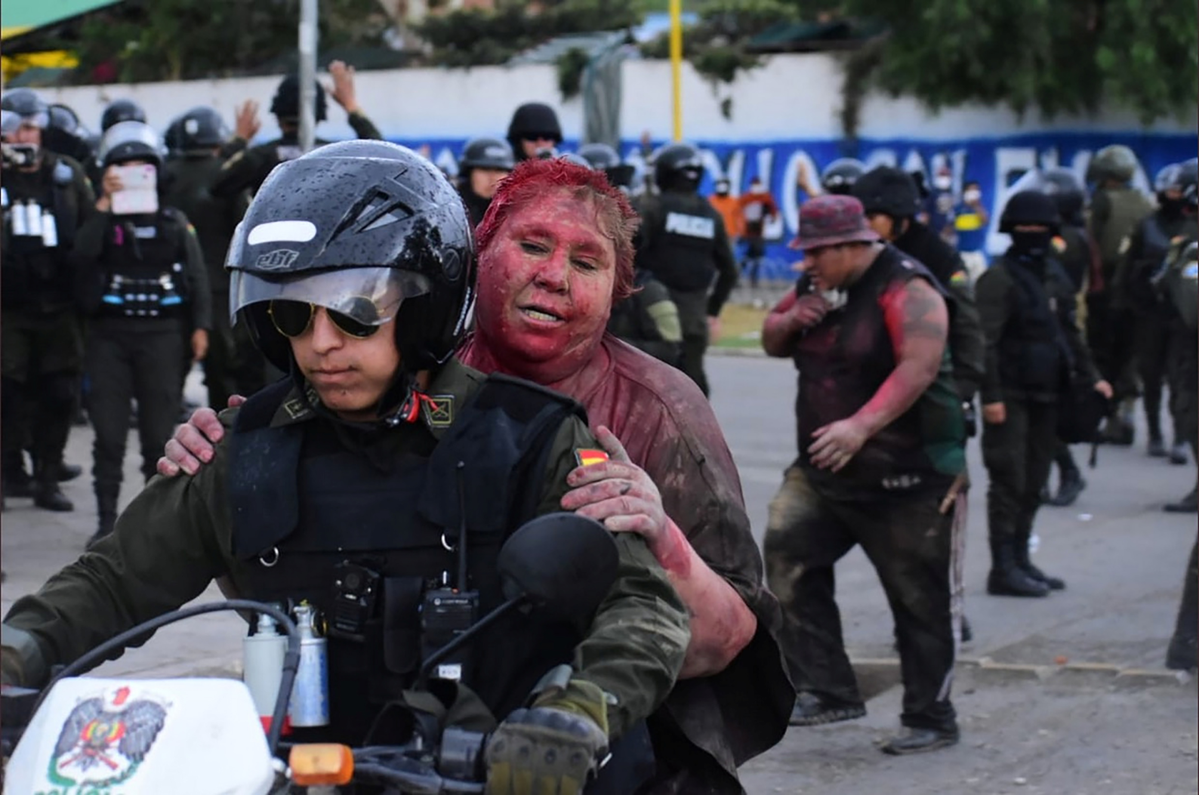 Police rescue Vinto mayor Patricia Arce Guzman on a motorcycle after people threw paint and dirt on her following a fire in Vinto's Town Hall in Bolivia