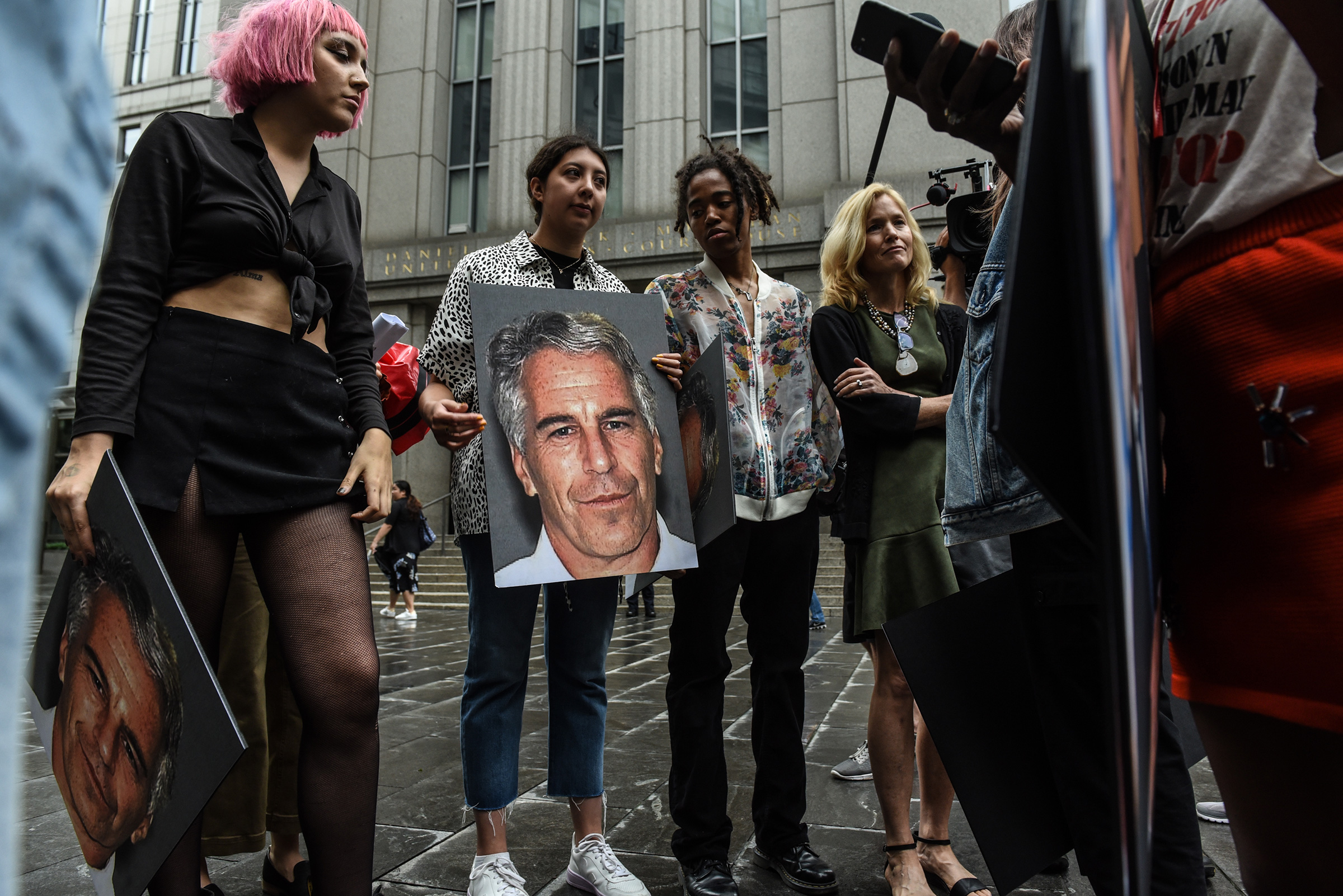 A protest group holds up signs of Jeffrey Epstein in front of the federal courthouse in New York City, July 8, 2019