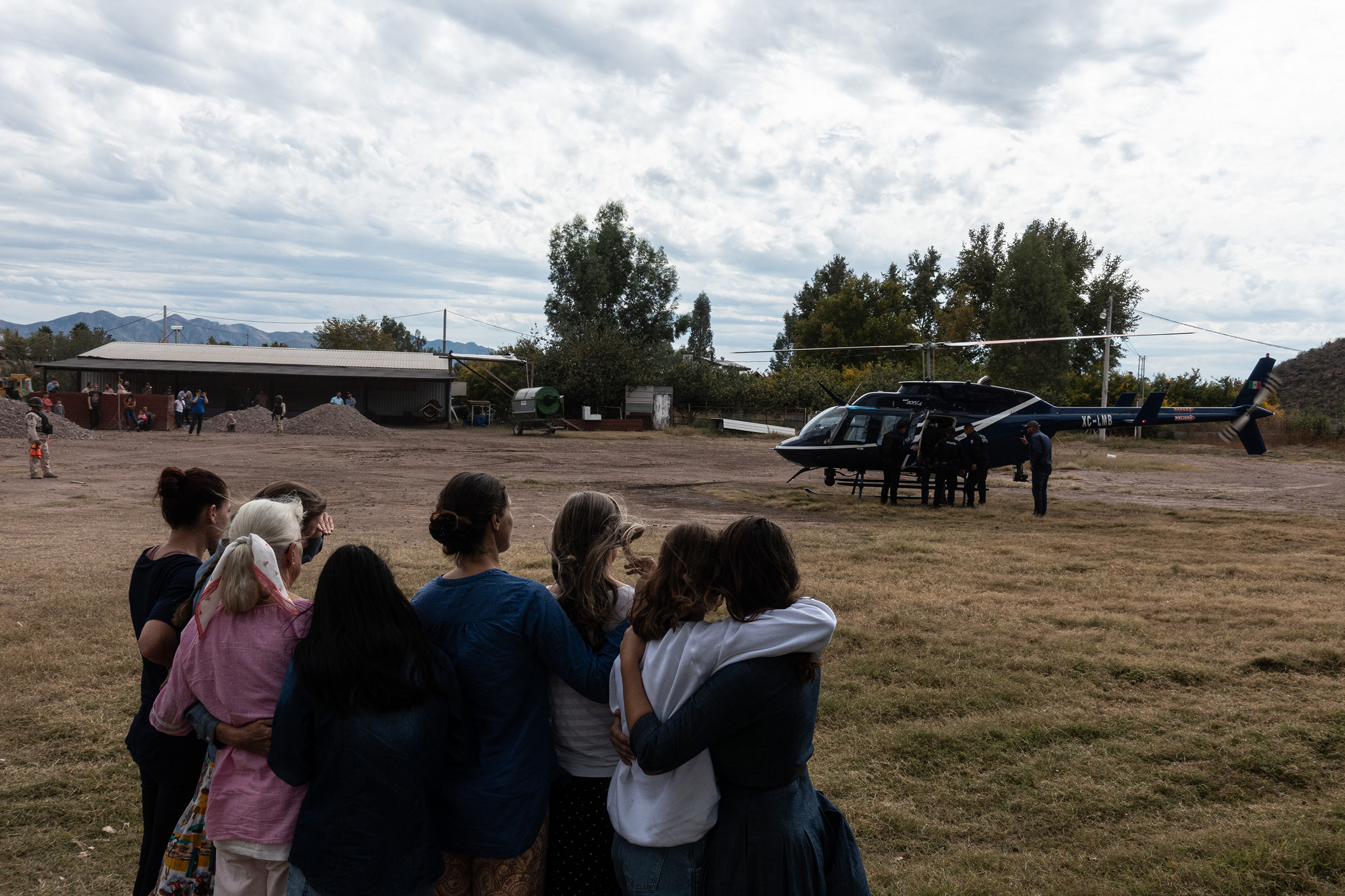 Family members watch a helicopter prepare to leave with the body of Christina Langford Johnson. (César Rodríguez—El País)