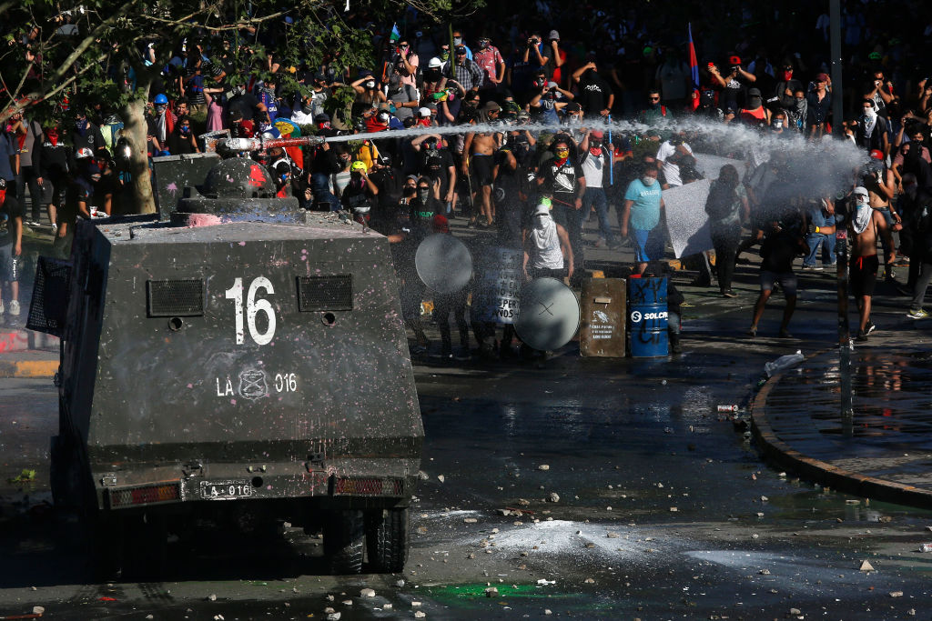 A riot police truck fires water to demonstrators during the ongoing protests against policies of Sebastian Piñera and longstanding inequality on Nov. 15, 2019 in Santiago, Chile. Chilean lawmakers agreed on calling a referendum in April 2020 to replace the current constitution, which was written and approved during General Augusto Pinochet's military dictatorship in 1980. People will be asked if they approve the idea of a new constitution and if current lawmakers should work on the redraft of the document. (Marcelo Hernandez&mdash;Getty Images)