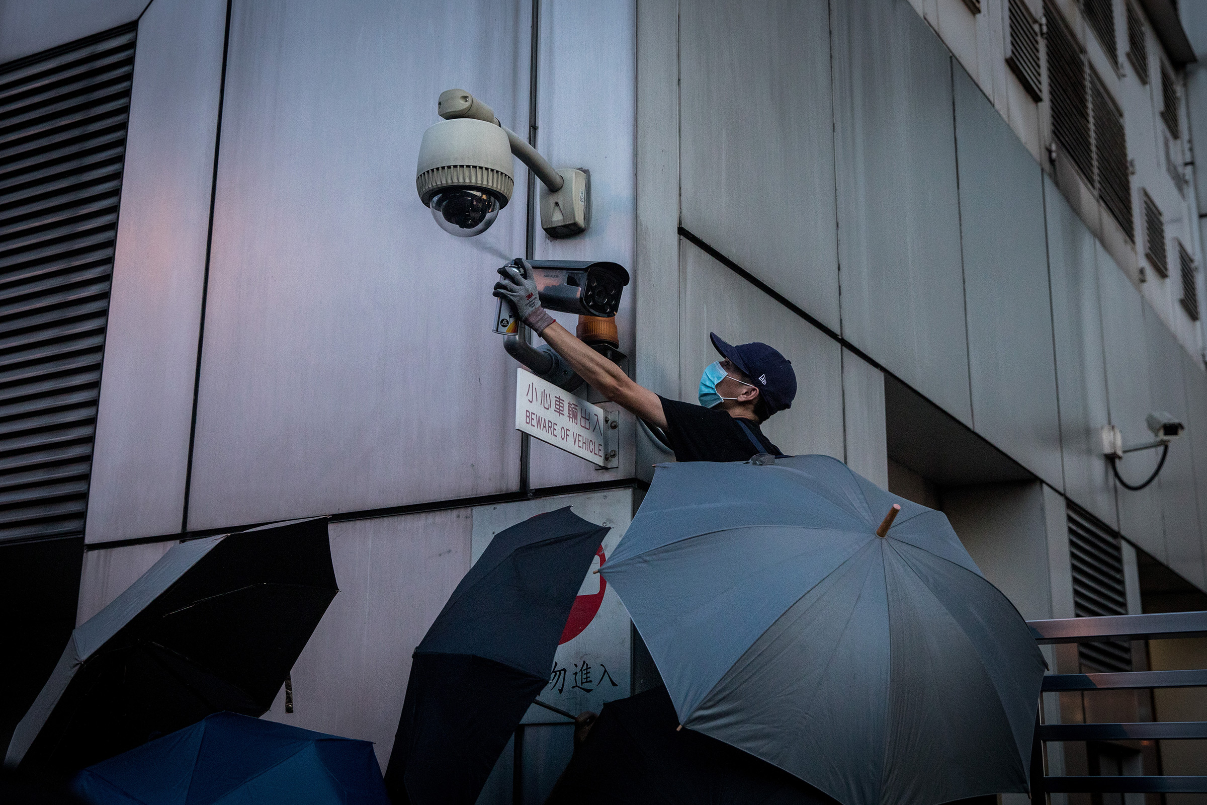 A protester covers a camera outside a government office in Hong Kong in July
