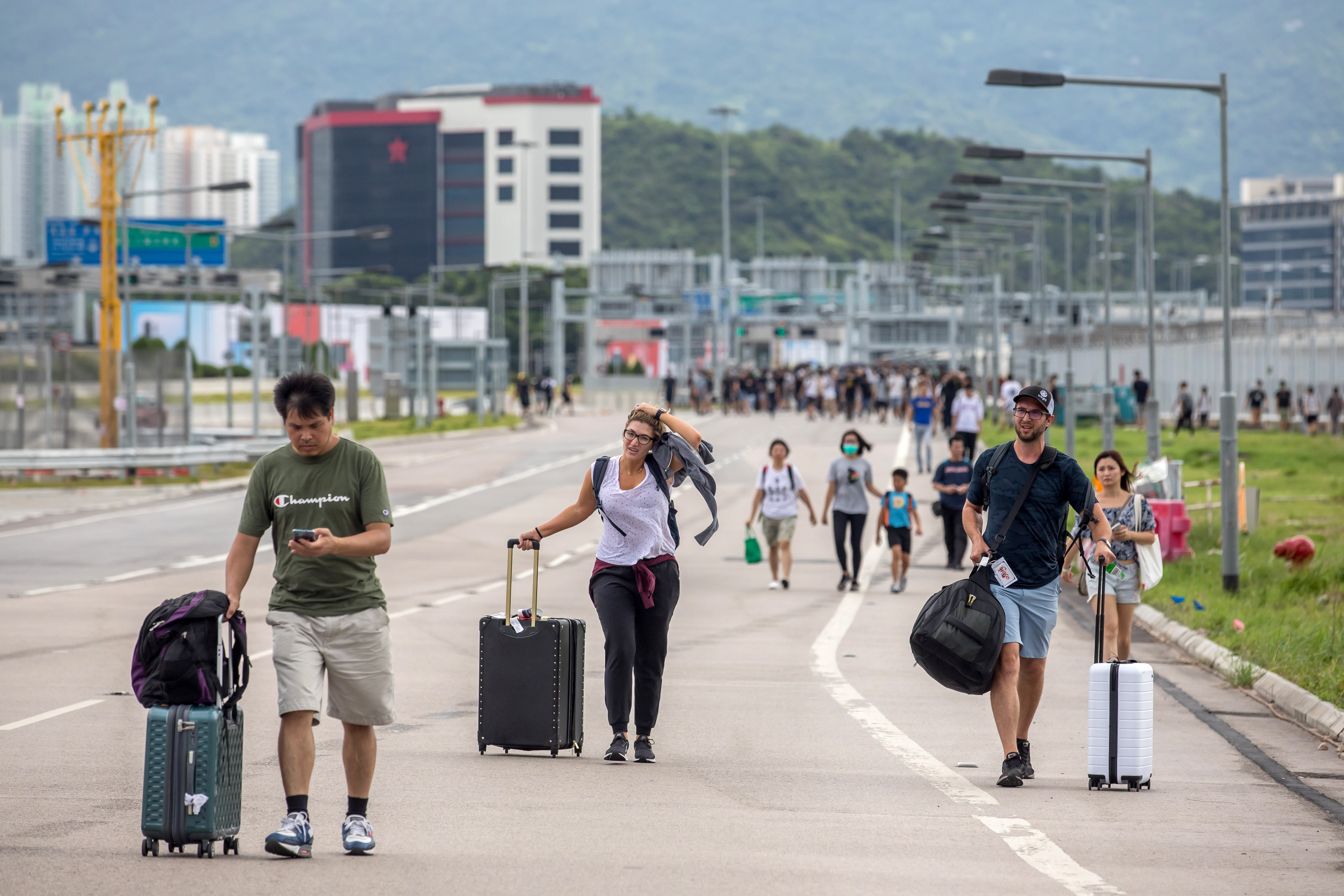 Travelers walk with their luggage along a road towards the Hong Kong International Airport during a protest in Hong Kong, China, on Sunday, Sept. 1, 2019. (Paul Yeung/Bloomberg via Getty Images)
