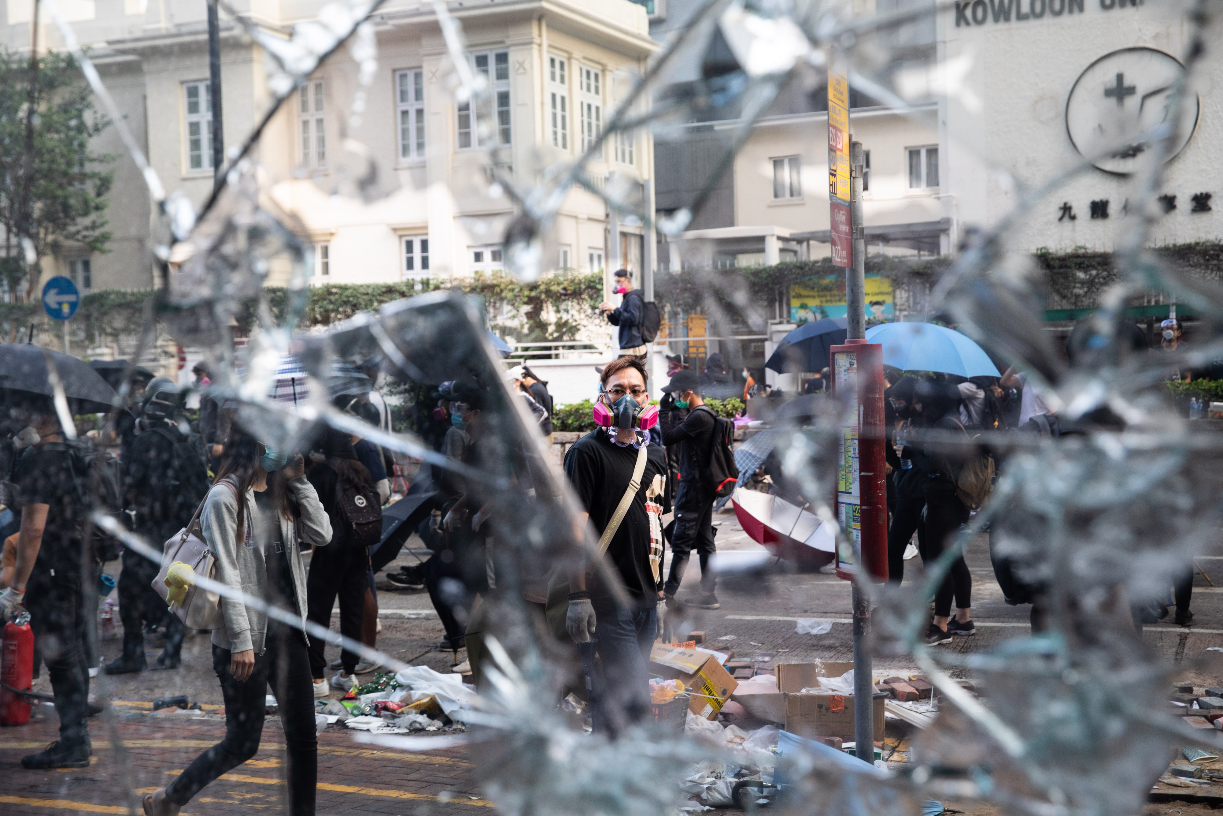 A protester stands in front of a broken pane of glass during a demonstration in Jordan district of Hong Kong, China, on Monday, Nov. 18, 2019. (Kyle Lam/Bloomberg via Getty Images)