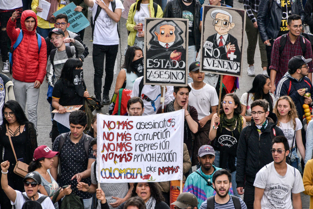 Anti-government demonstrators march holding sign calling for no more assassinations, corruption, repression and privatization Nov. 21, 2019 in Bogota, Colombia. (Guillermo Legaria Schweizer/Getty Images)