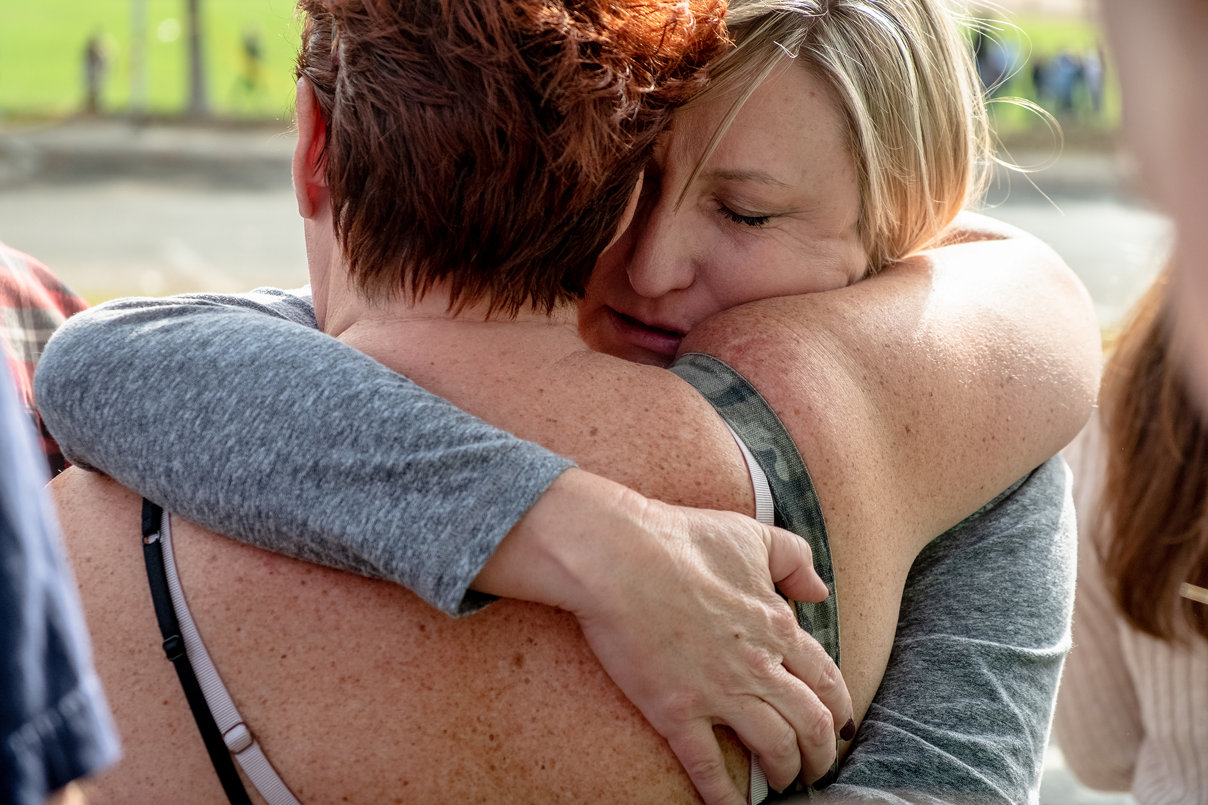 Christine Heffernan embraces her friend while waiting for her son, Alex Cox, 17, a student at Saugus High School, to arrive to the reunification center.