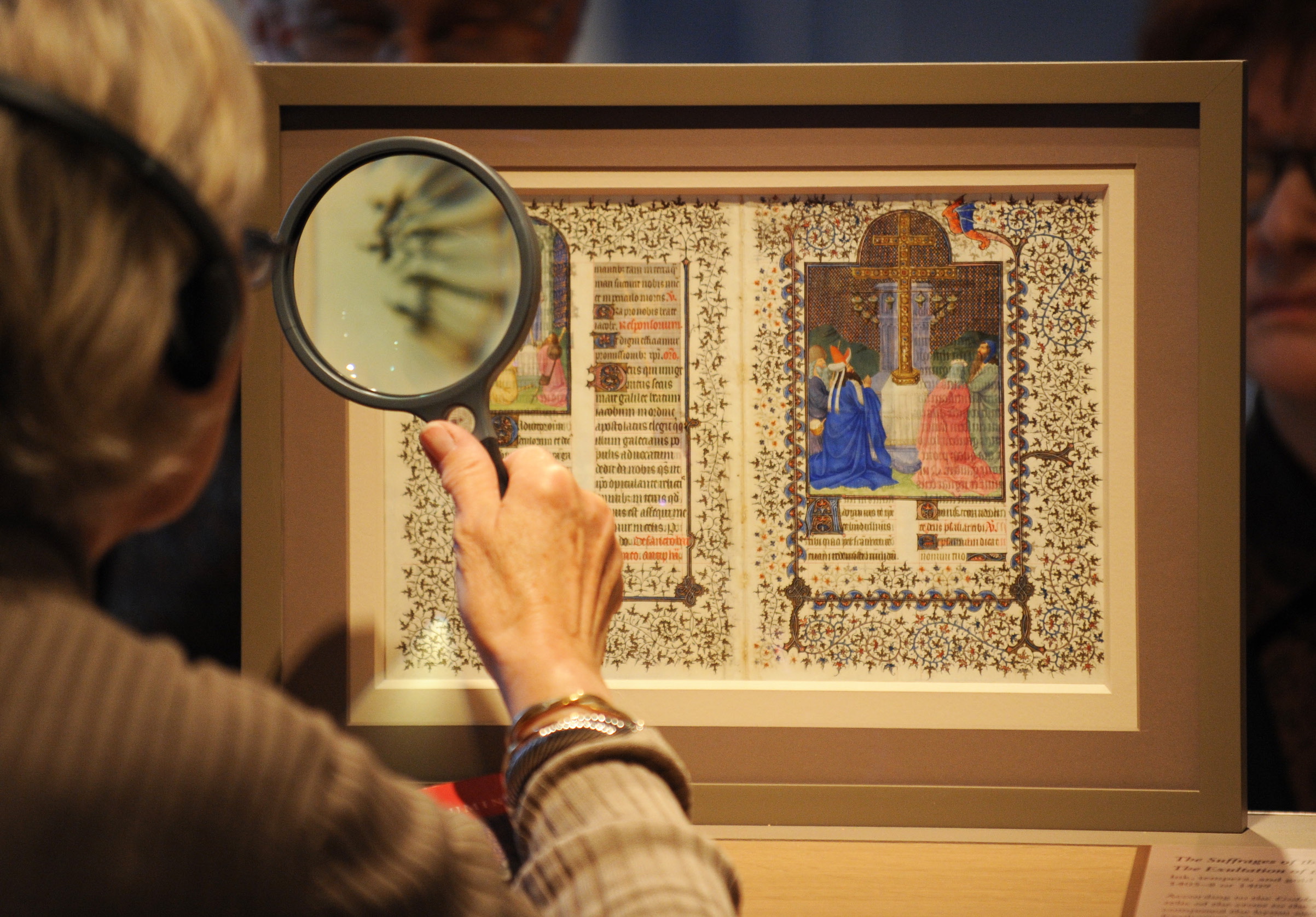 A woman uses a magnifying glass to view pages from a medieval prayer book known as the Belles Heures, on in 2010 at the Metropolitan Museum of Art in New York City. (Stan Honda—AFP via Getty Images)