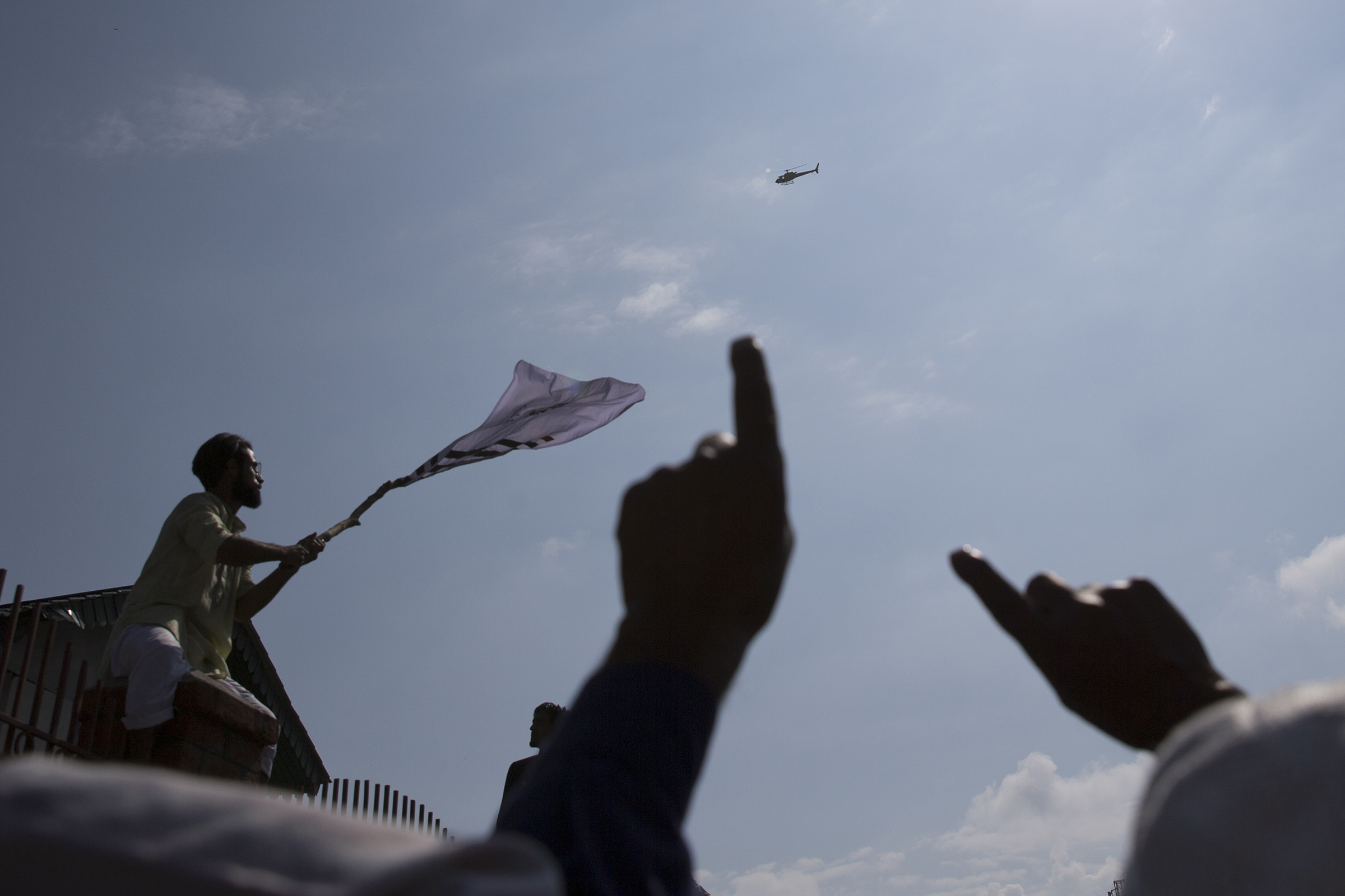 A Kashmiri protester waves a flag as Indian authorities in a helicopter monitor a protest after Eid prayers in Srinagar, Indian controlled Kashmir, on Aug. 12, 2019. (Dar Yasin—AP)