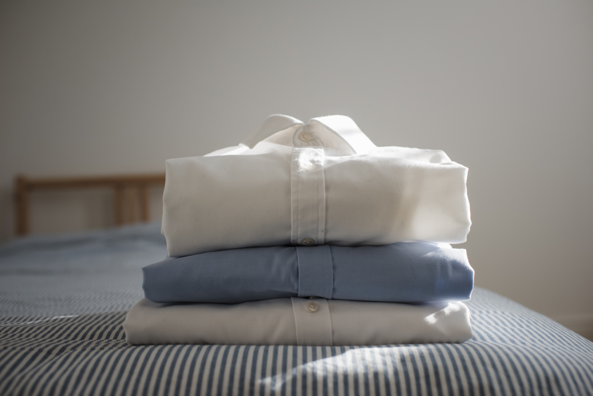 Close-up of folded shirts stacked on bed at home